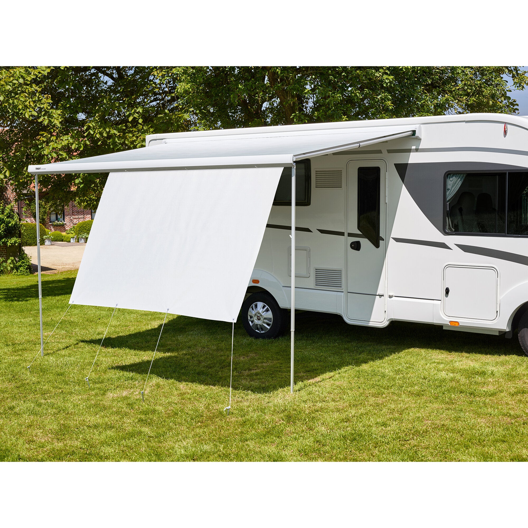 Weißes Wohnmobil mit ausgefahrener Markise und frontalem Sichtschutz Thule View Blocker Front 4,30 m sichtbar, steht auf grünem Rasen