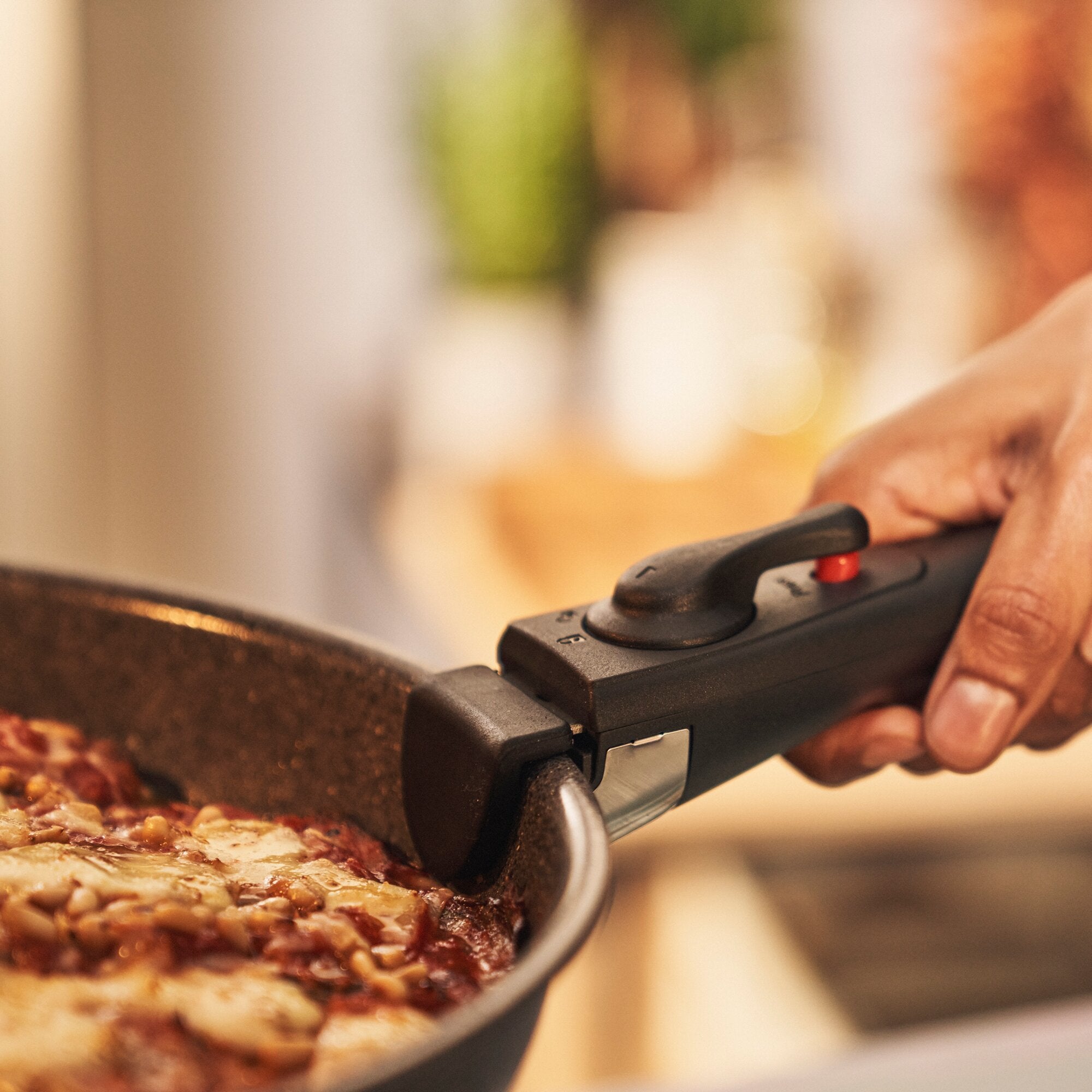 Nahaufnahme einer Bratpfanne Torre mit Griff, in der Hackfleisch brät; eine Hand hält den Griff