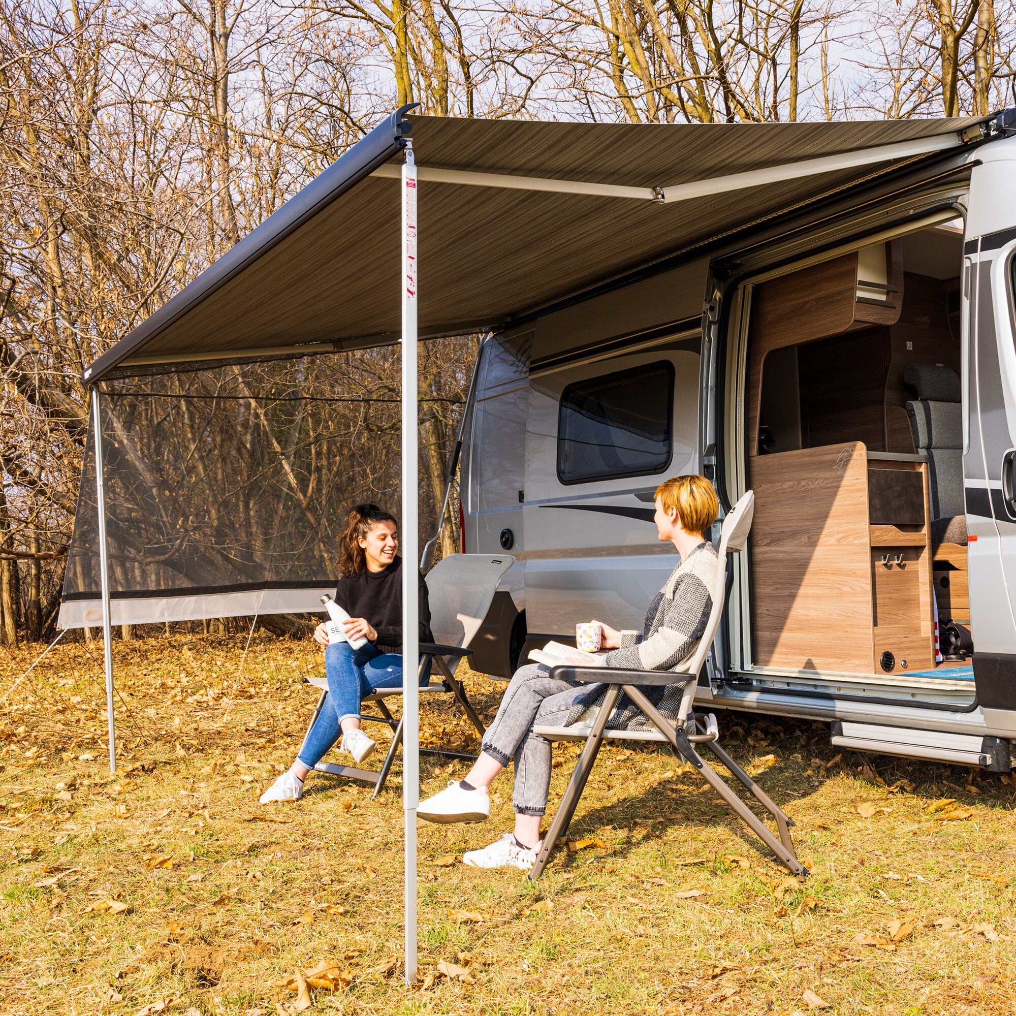 Seitenwand Sun View Side, 230 cm, am Seitenbereich einer Wohnmobil-Markise angebracht, transparente Wand mit Fenster, davor sitzen zwei Personen