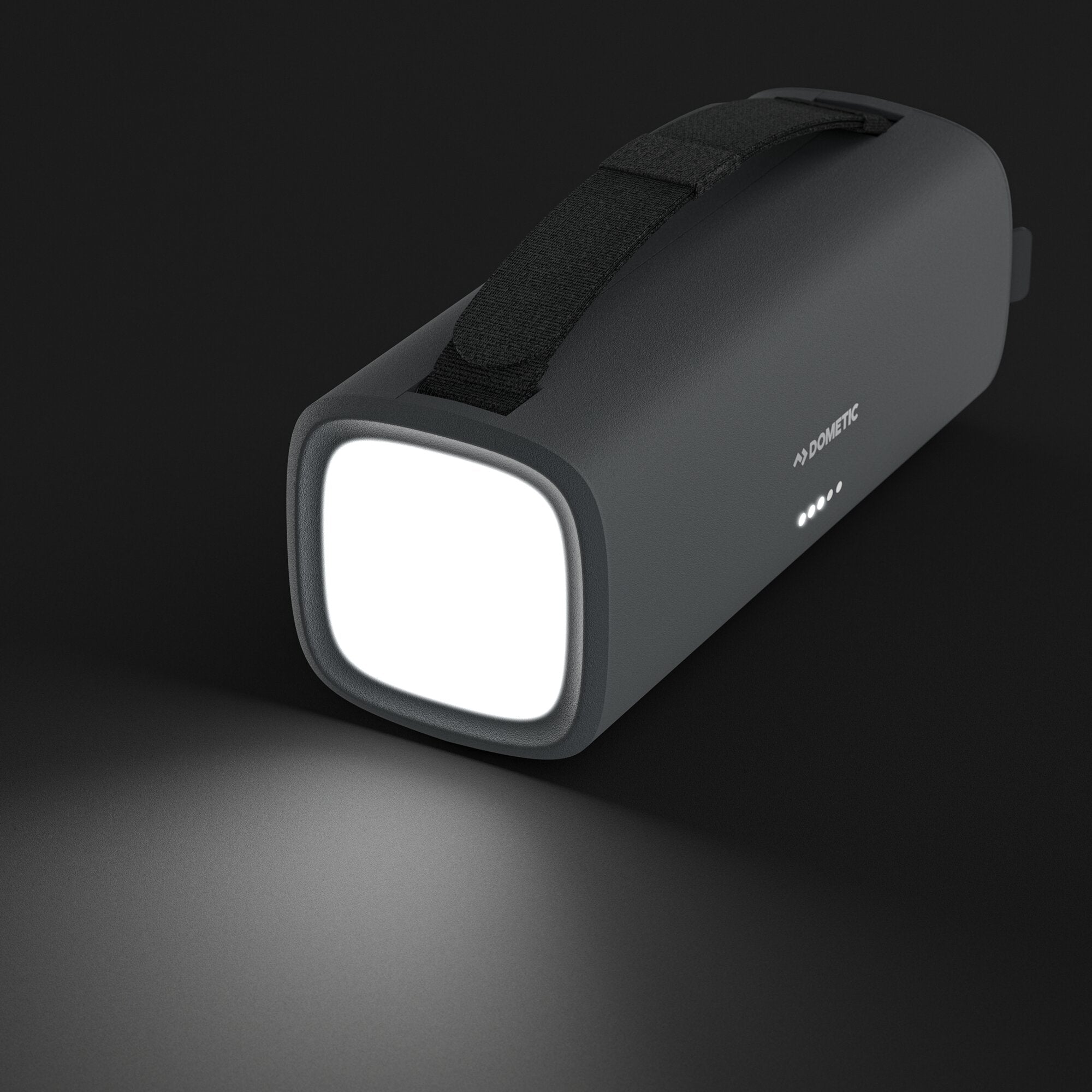 Powerbank PLB15 mit Taschenlampe in dunklem grauen Gehäuse, Trageschlaufe sichtbar, Frontlicht leuchtet, LEDs an der Seite, DOMETIC-Logo