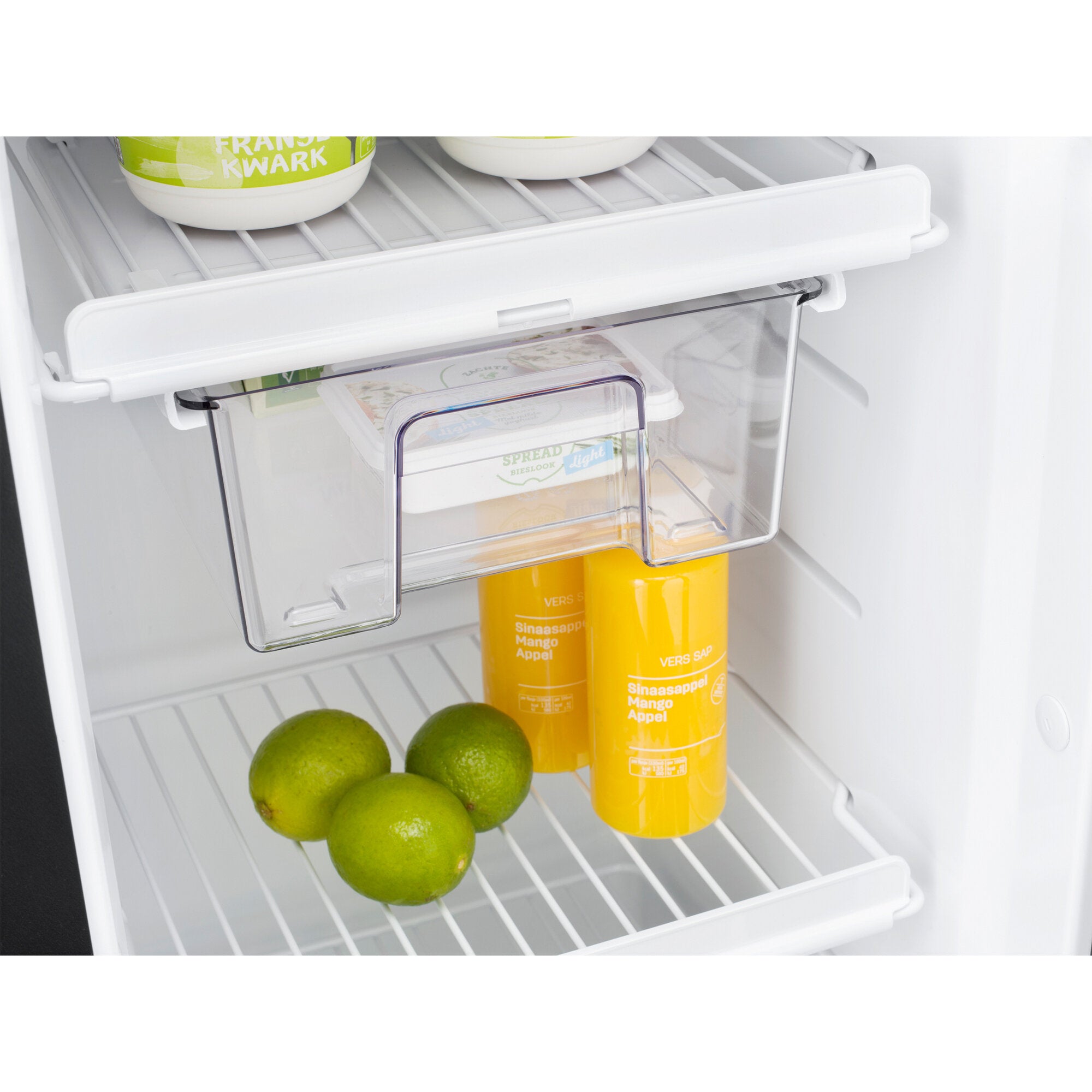 Innenraum eines kleinen Kühlschranks mit zwei weißen Schalen auf der oberen Ablage, transparente Boxen darunter, unten Limetten und gelb-orange Dosen