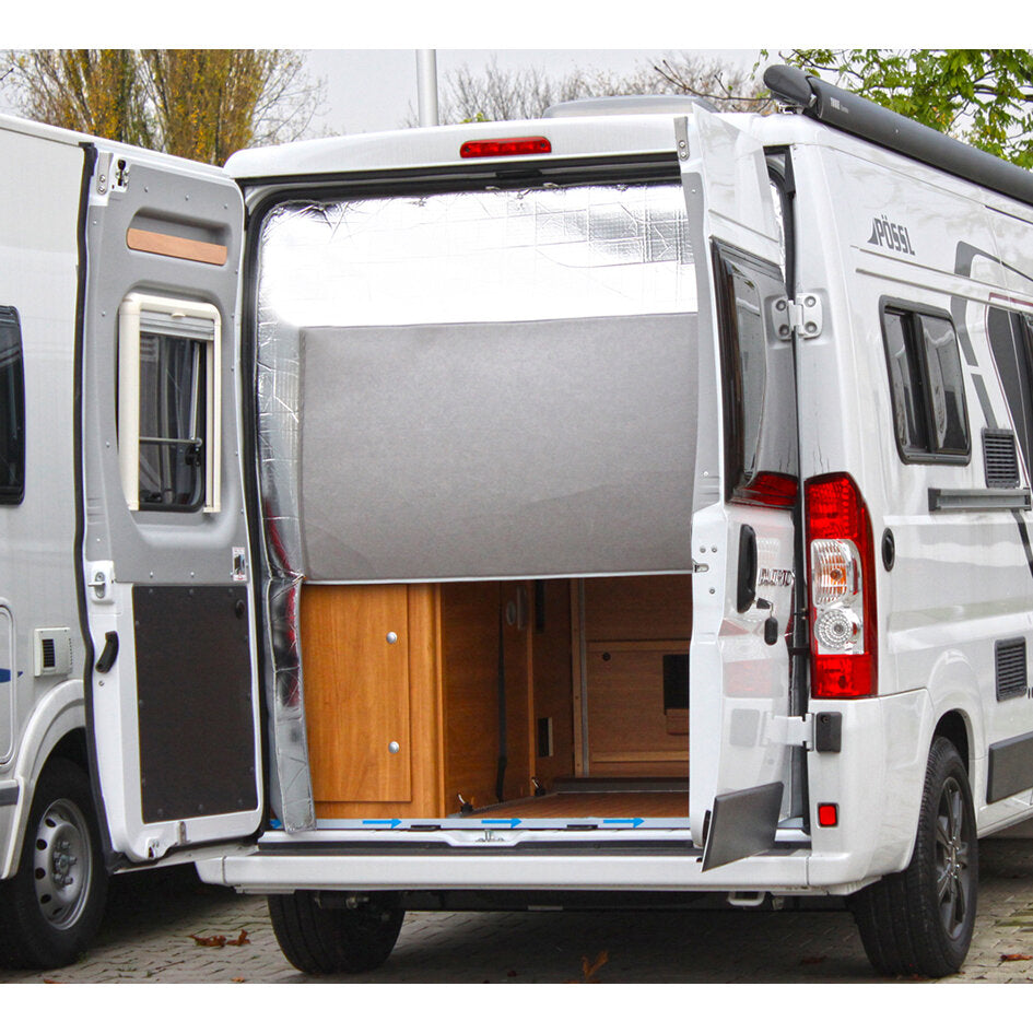 Weißer Wohnmobil-Van mit offener Hecksektion; silberner Thermovorhang als Isolationsabdeckung hinter der Tür, Holzschränke im Innenraum sichtbar