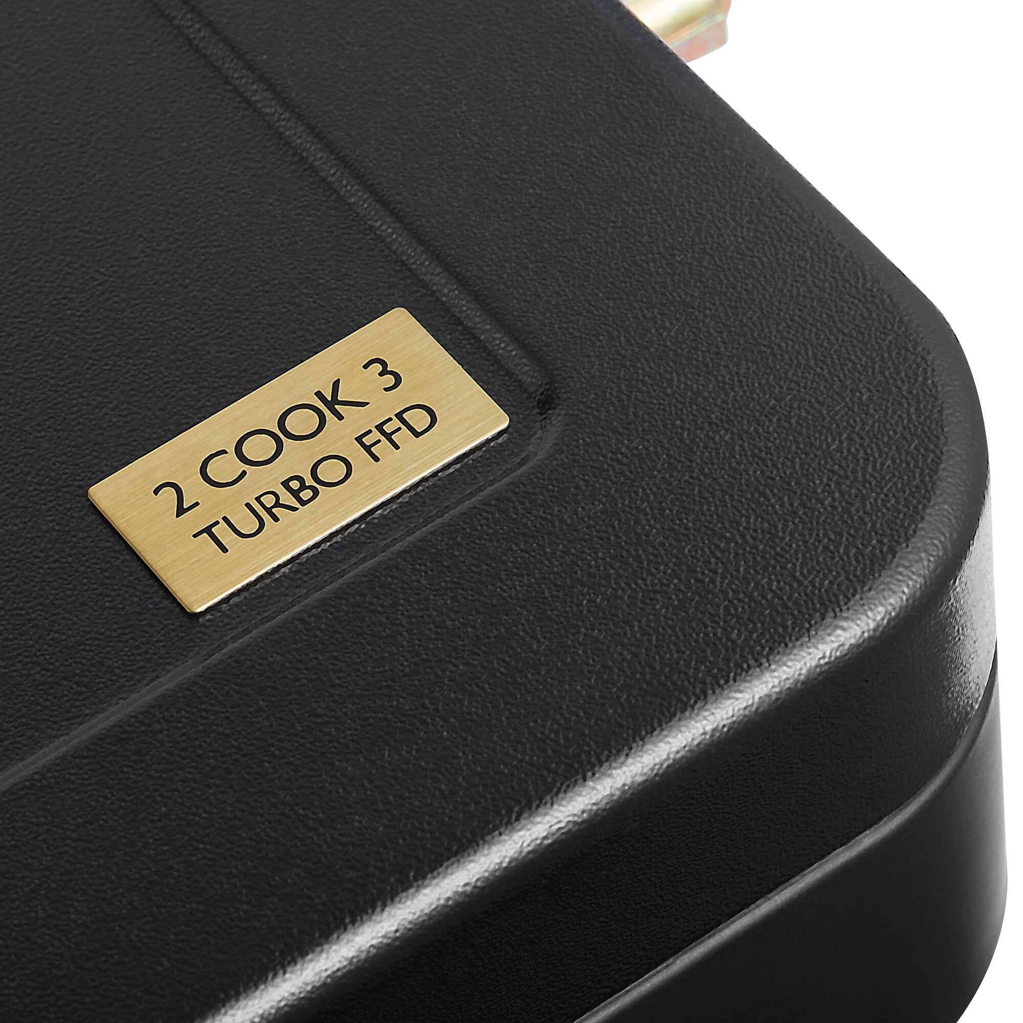 Detailaufnahme eines schwarzen Gehäuses mit lederähnlicher Oberfläche und sichtbarer Naht, goldene Plakette mit der Aufschrift 2 COOK 3 TURBO FFD, obere Kante sichtbar