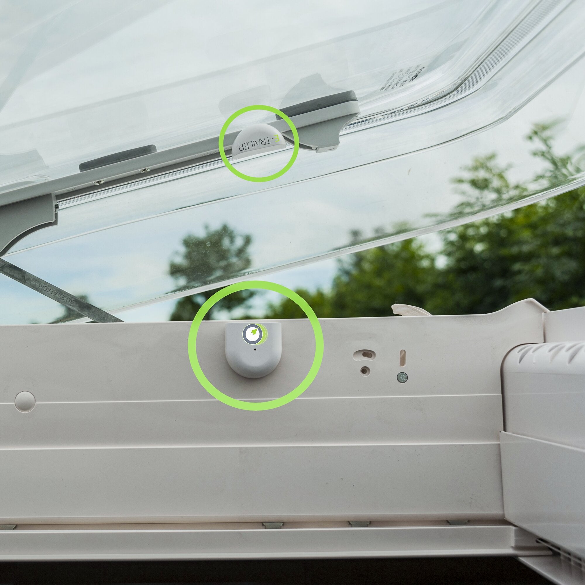 Ein grauer E-Switch Sensor zur Fenster- und Türüberwachung ist am Fensterrahmen montiert, mit grünem Statusindikator