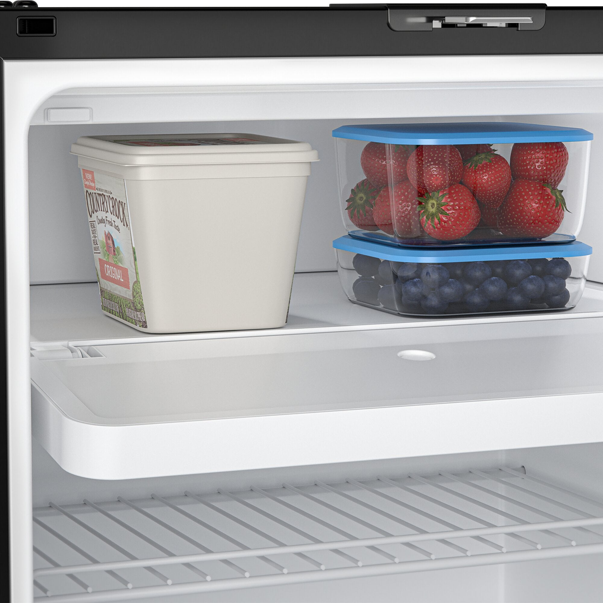 Kühlschrankinnenraum mit zwei transparenten Behältern und blauen Deckeln, gefüllt mit Erdbeeren und Blaubeeren