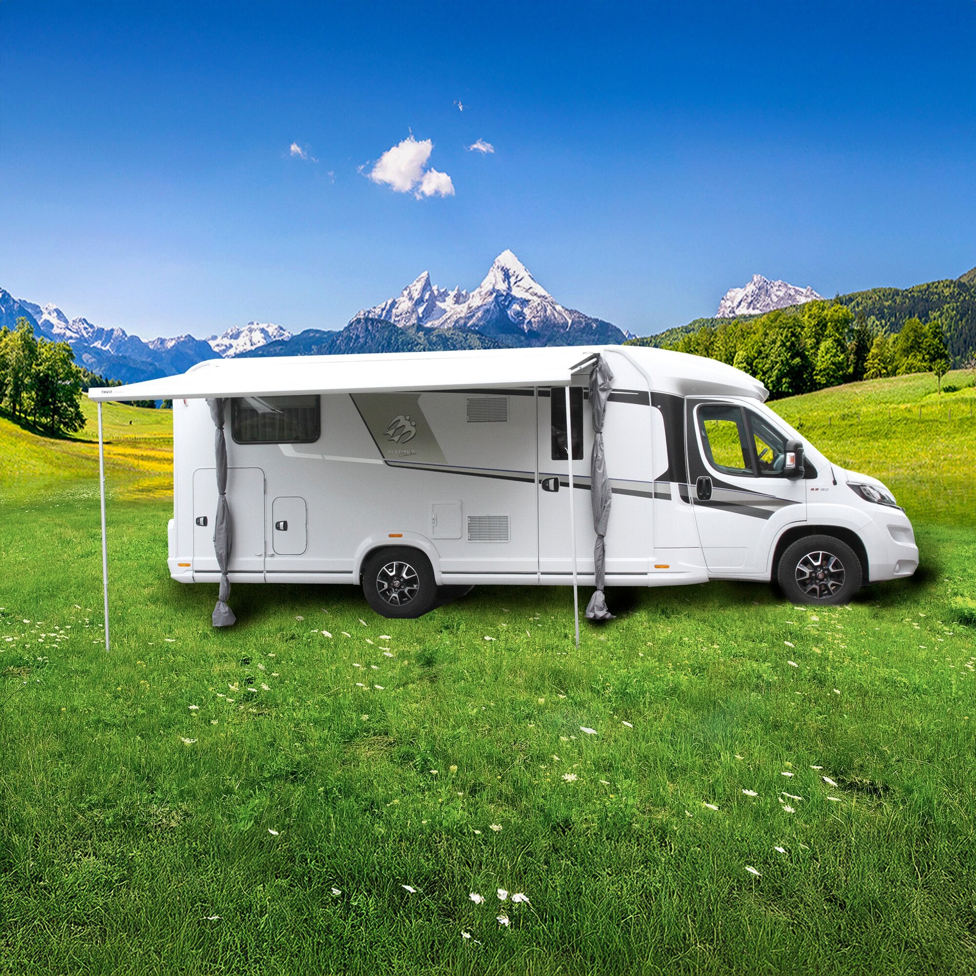 Weißer Wohnmobil mit ausgefahrenem Markisenzelt Camper Lounge, auf grünem Rasen vor Bergen und blauem Himmel