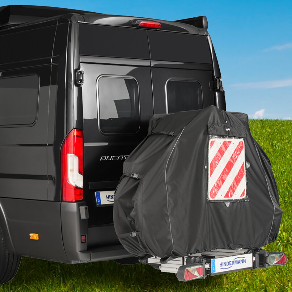 Schwarze Fahrradschutzhülle Concept Blackline deckt zwei Downhill-Bikes auf dem Heckträger eines Vans, mit rot-weiß gestreiftem Reflektorfeld