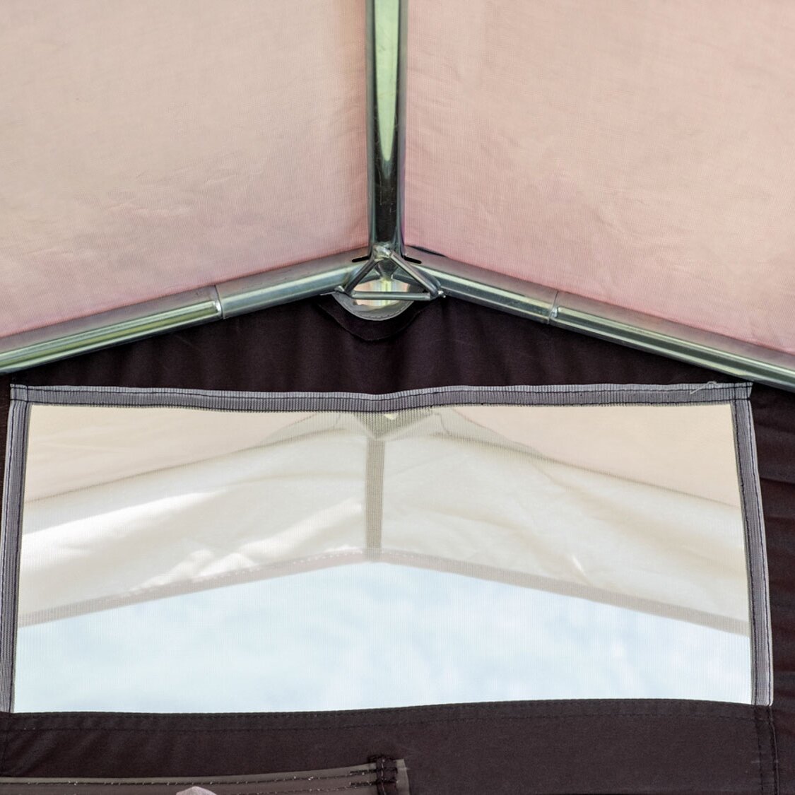 Innenansicht eines aufgeklappten Küchenzeltes mit silbernem Metallrahmen, pinken Seitenwänden und einem Fenster mit Netzgewebe