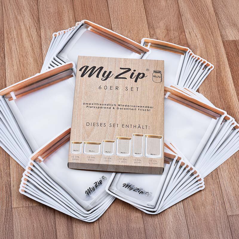 Auf dem Holzboden liegende Verpackung des My Zip 60-tlg. Sets, umgeben von zahlreichen transparenten Aufbewahrungsbeuteln mit weißem Rand