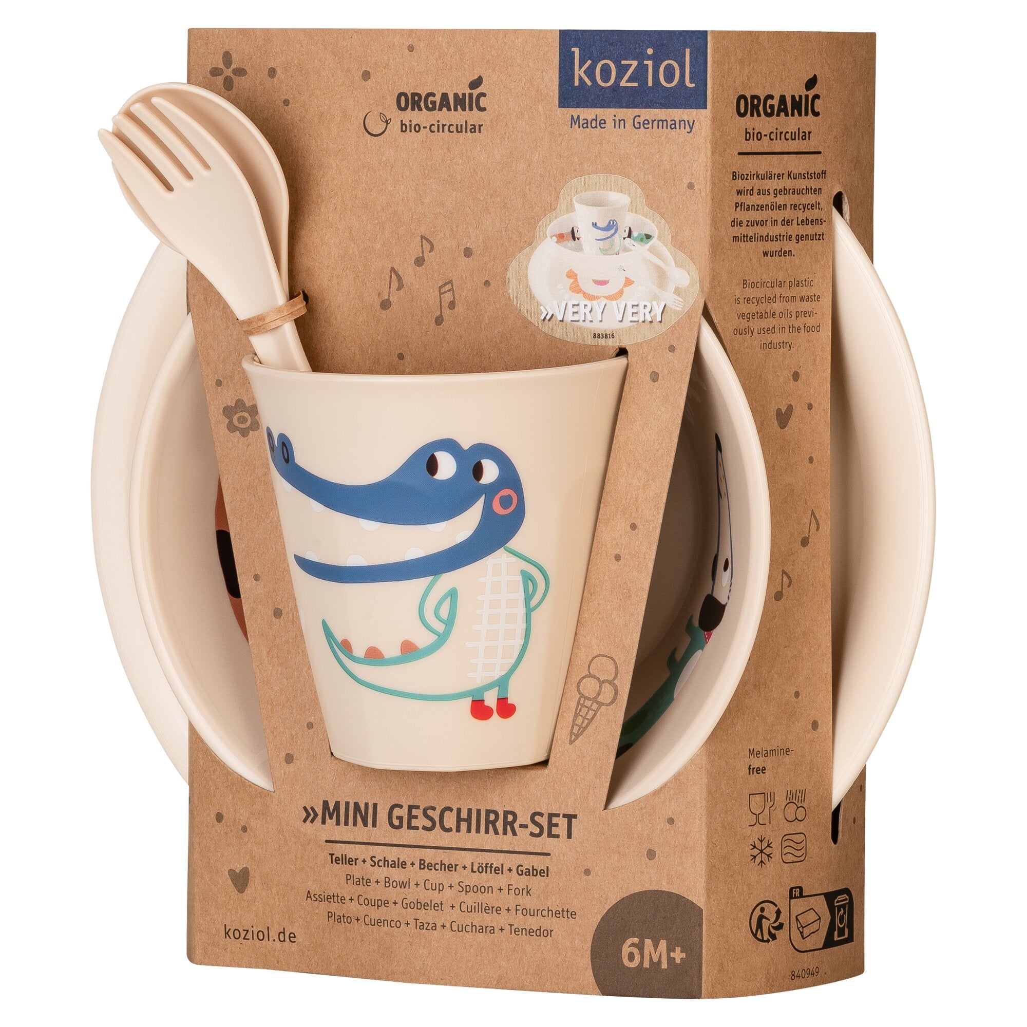 4-teiliges Kindergeschirr-Set von koziol, Becher mit blauem Krokodil-Motiv, beige Löffel und Gabel an brauner Kartonverpackung befestigt, 6M+