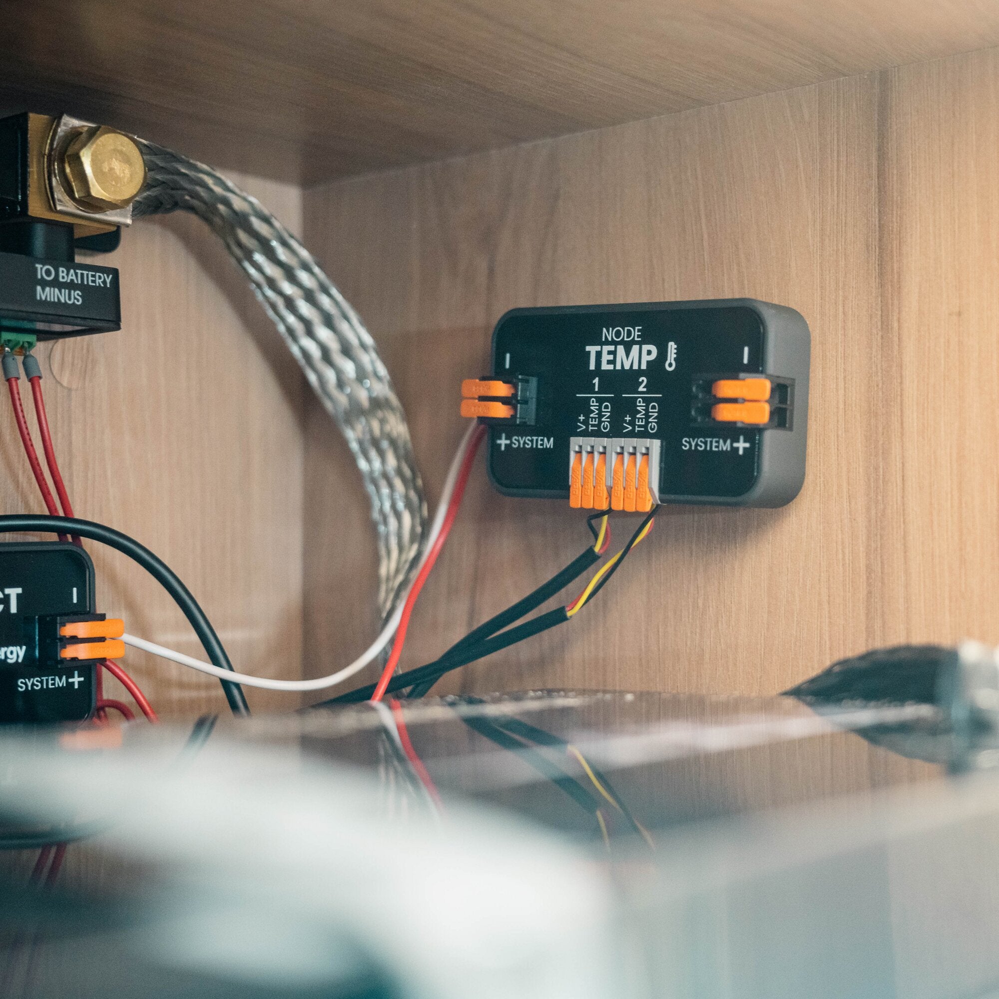 Innenansicht eines Holzschranks mit schwarzer Elektronik, verzinnten Kabeln, goldener Schraubklemme und orangefarbenen Klemmleisten; NODE TEMP