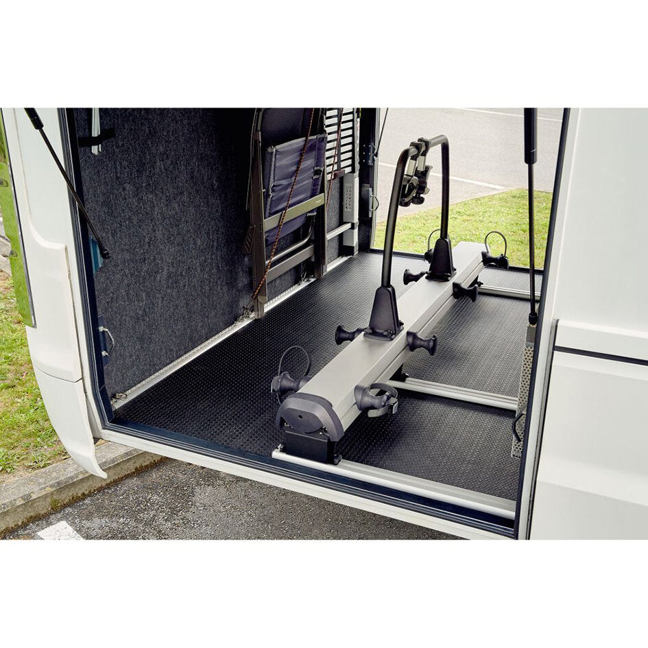 Innenraum eines Transporters mit Thule VeloSlide Short Fahrradträger; silbergraue Schiene, Halterarme und rutschfeste Bodenmatte sichtbar