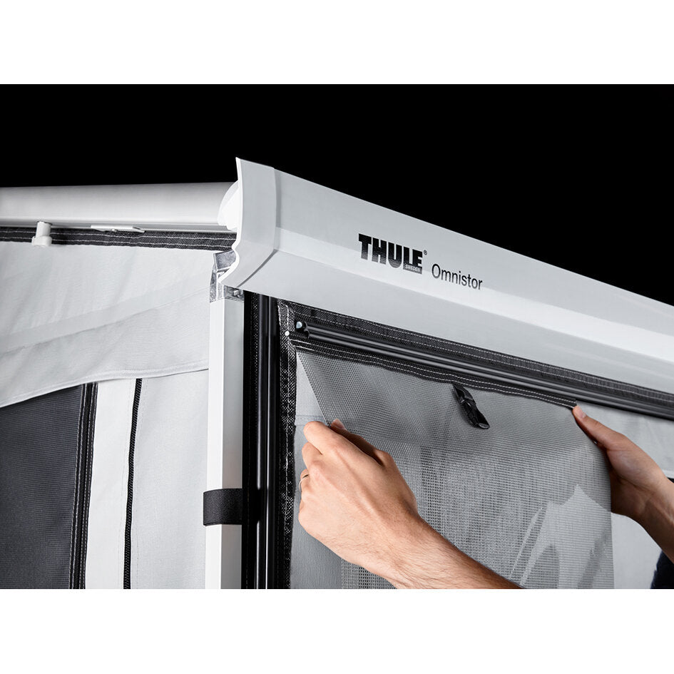 Vorderteil der Thule Residence G3 Markise, weißer Aluminiumrahmen mit Thule Omnistor Logo; Person platziert Netzfenster mit Reißverschluss am Rahmen