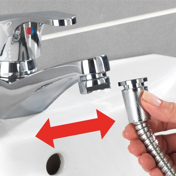 Chromfarbene Waschbeckenbrause mit flexiblem Spiralschlauch, in einer Hand gehalten, neben dem Wasserhahn am Spülbecken