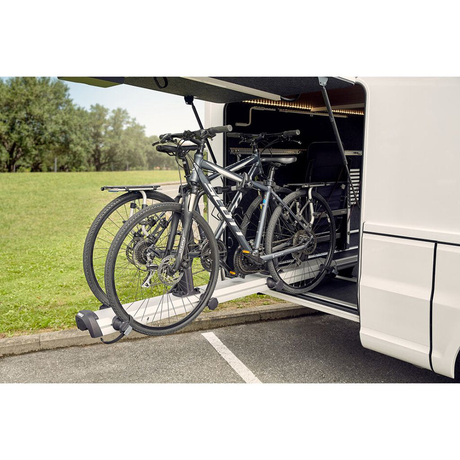 Außenansicht eines Wohnmobils mit ausziehbarem Fahrradträger Thule VeloSlide Short Version, auf dem zwei Mountainbikes befestigt sind