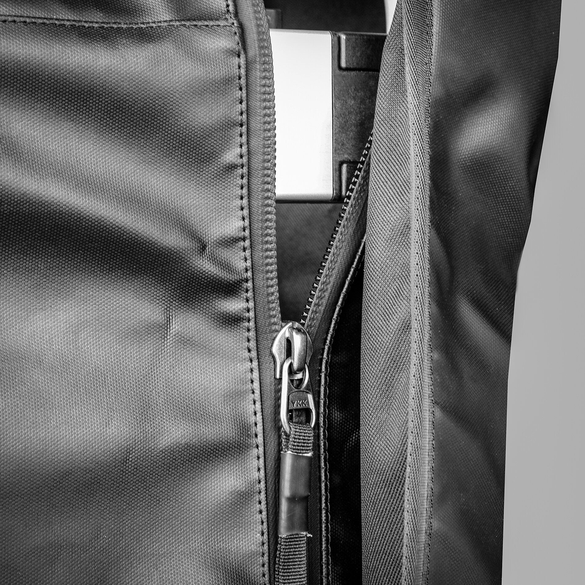 Detailaufnahme einer schwarzen Transportbox aus Textil mit offenem Reißverschluss und einem Tragegurt aus Webstoff