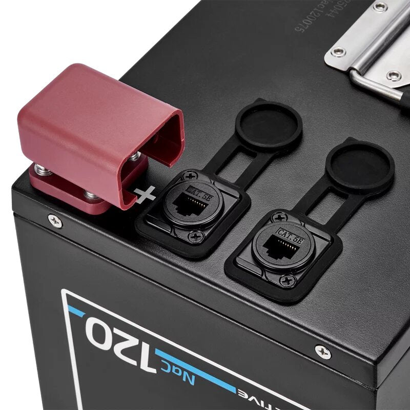 Nahaufnahme einer schwarzen Batterie mit roter Schutzkappe über dem Pluspol, daneben zwei schwarze Abdeckkappen über den Terminalen