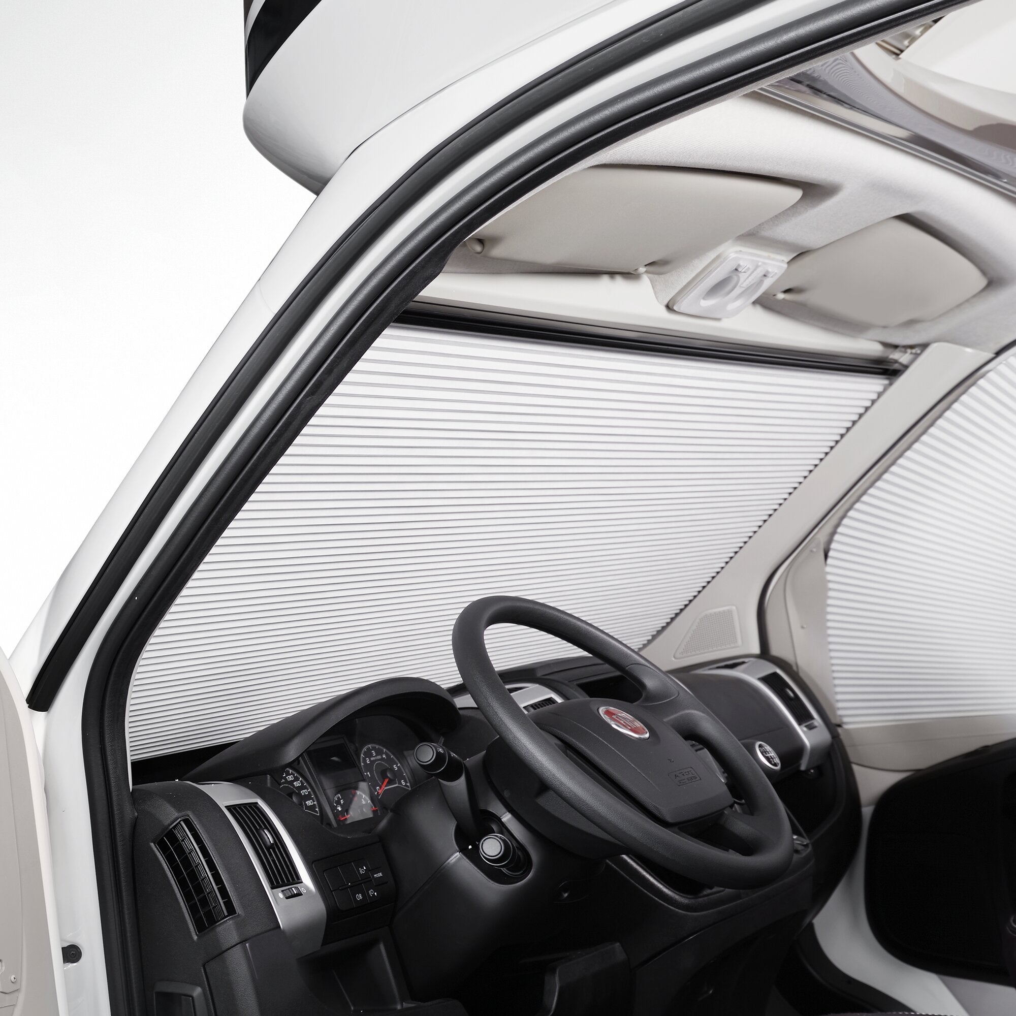 Innenraum eines Fiat Ducato mit Verdunkelungsrollo am Seitenfenster, Lenkrad, Armaturenbrett und grauer Deckenverkleidung sichtbar