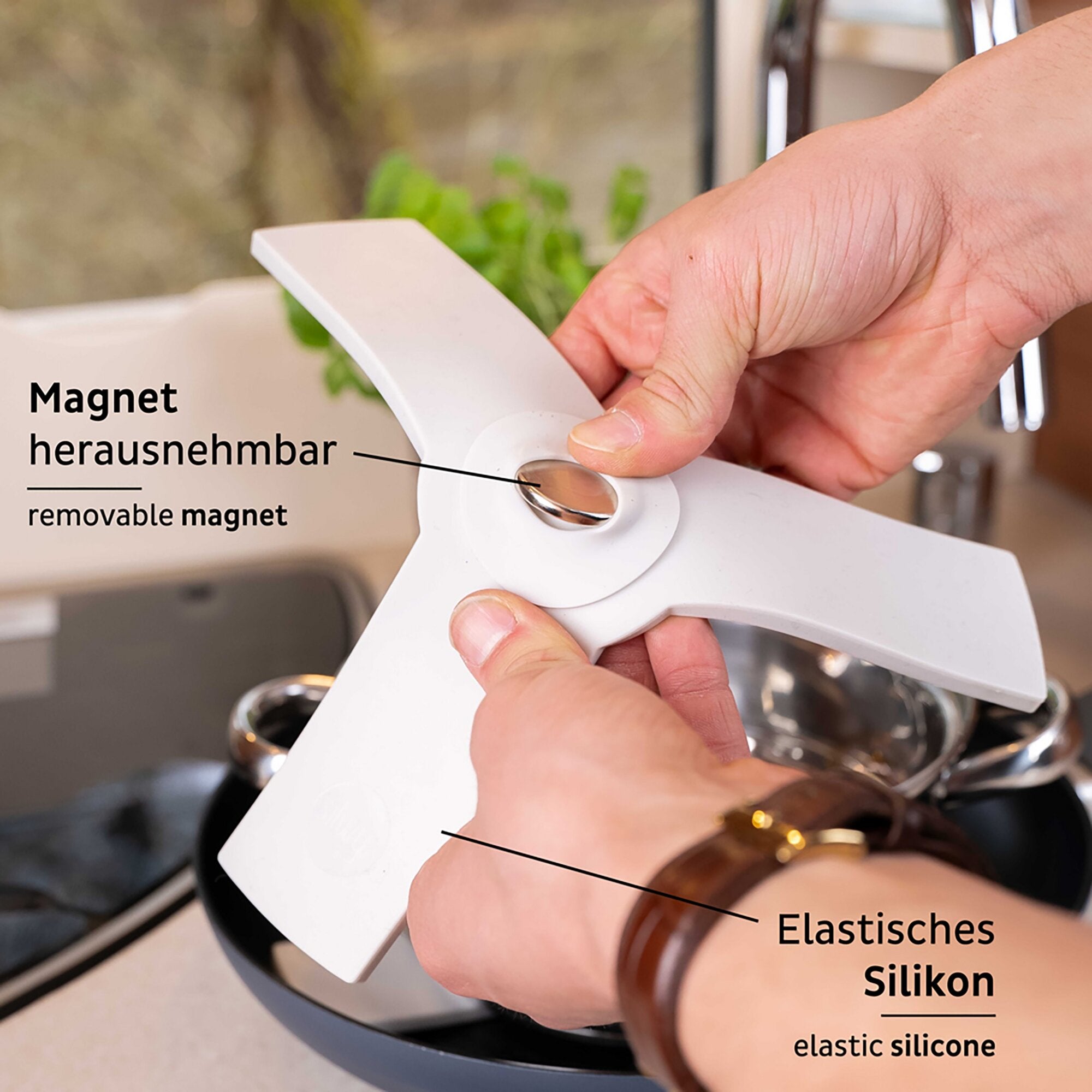 Nahaufnahme einer Hand, die einen Kunststoffarm eines Magnet-Sandwich hält; zu sehen ist ein herausnehmbarer Magnet und elastisches Silikon