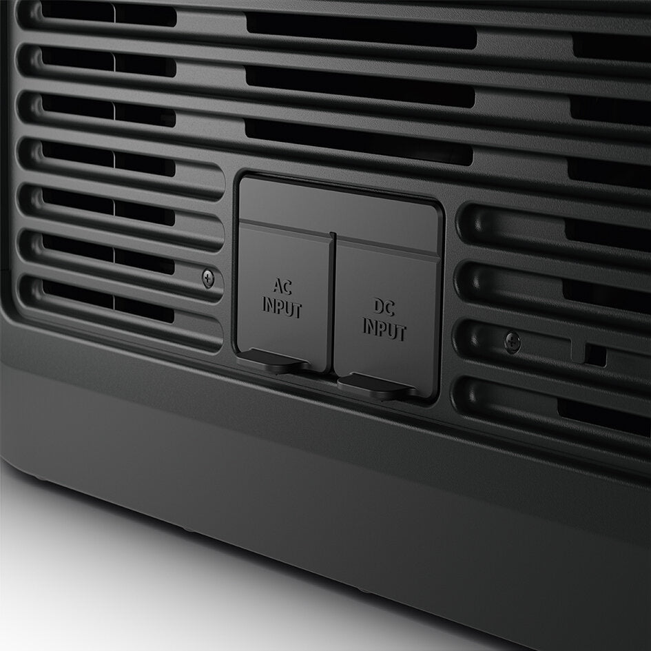 Nahaufnahme einer schwarzen Kühlbox mit Lüftungsschlitzen und zwei Abdeckklappen AC INPUT und DC INPUT