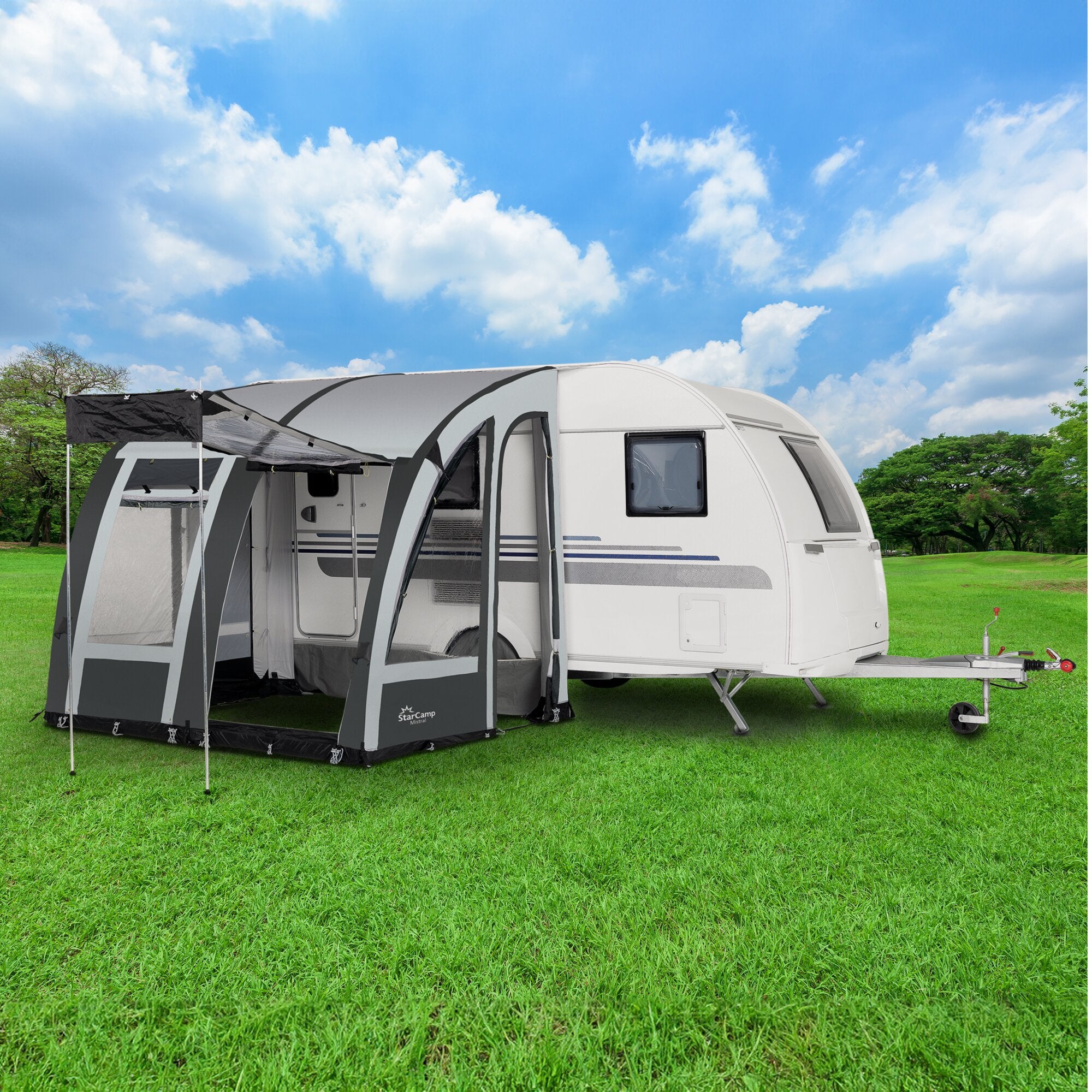Großes Reisevorzelt in Grau-Schwarz an einer weißen Caravan-Seite montiert, mit breitem Eingangsbereich, Fenstern, Treppenstufen und Gras unter blauem Himmel