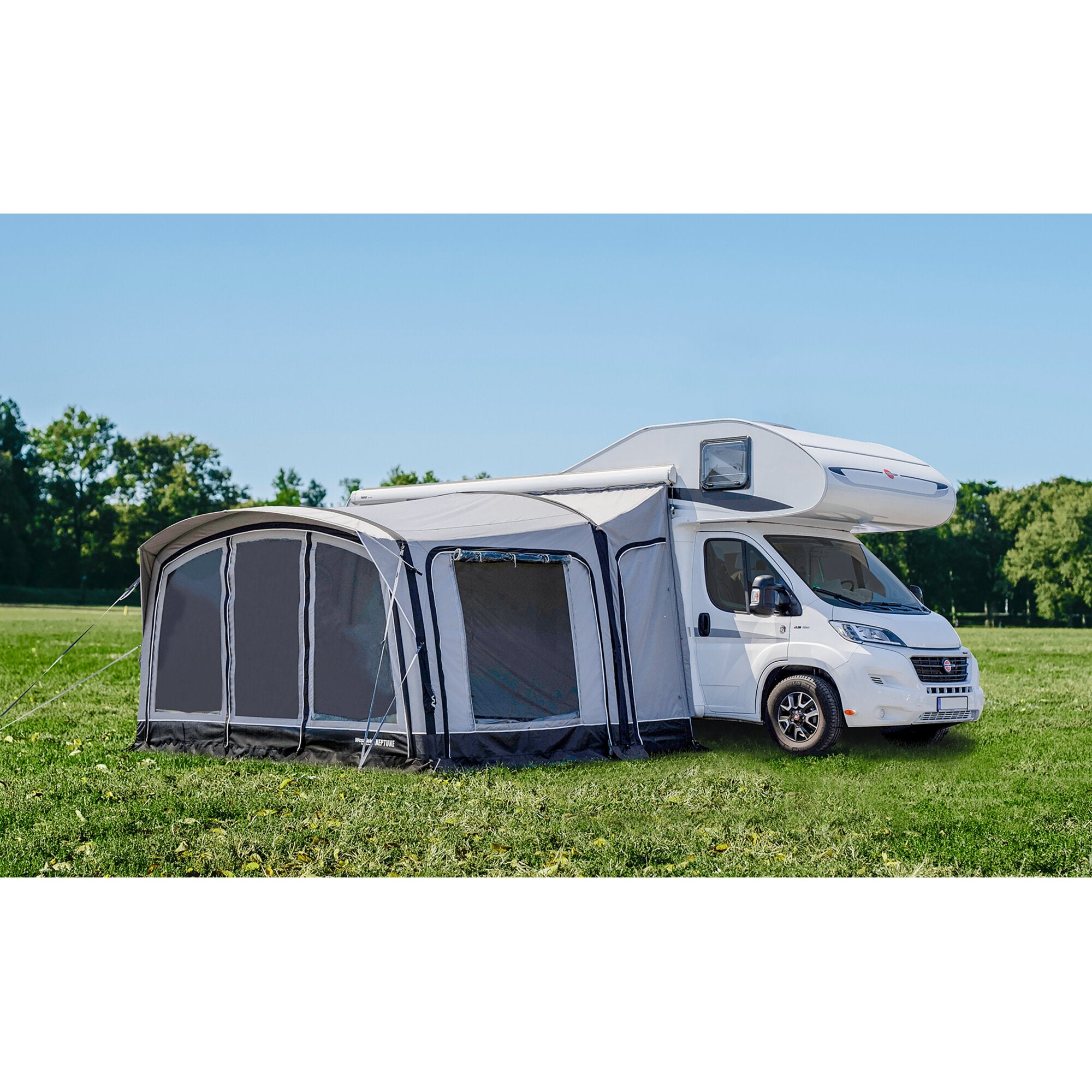 Weißes Reisemobil mit seitlich angebautem grauen Vorzelt Neptune 2.0, Abspannseile sichtbar, grüne Wiese und blauer Himmel im Hintergrund