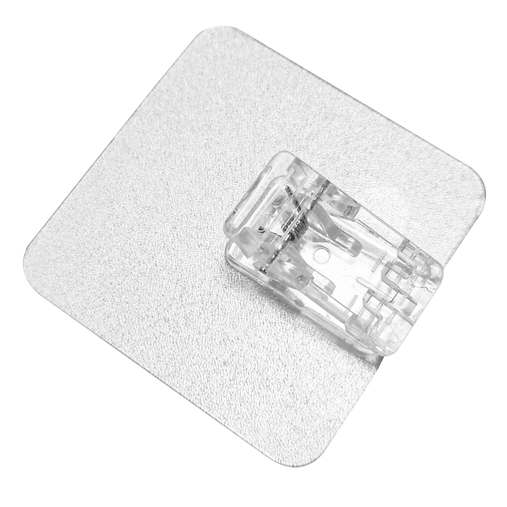 Detailaufnahme eines transparenten Mini-Hakenclips mit Federmechanik auf einer silbernen, strukturierten Platte Magische Haken Clip Mini