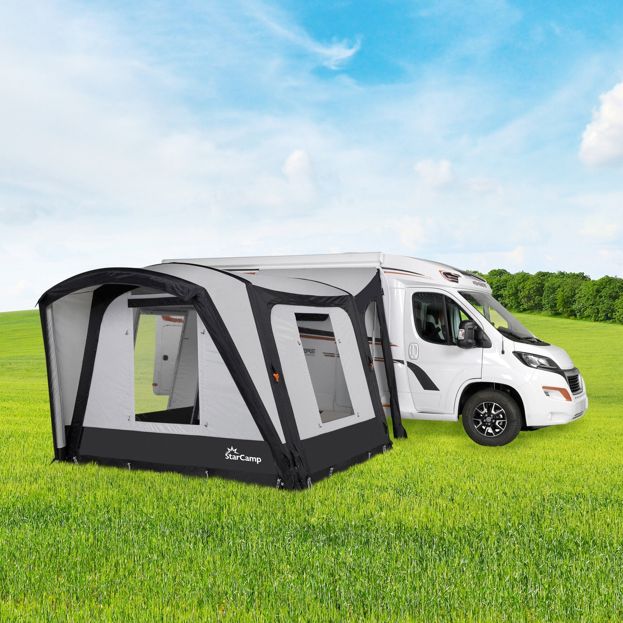 Weißes Wohnmobil mit seitlichem Anbauzelt in Grau, große Fenster, offener Eingangsbereich, StarCamp-Logo, grüne Wiese und blauer Himmel