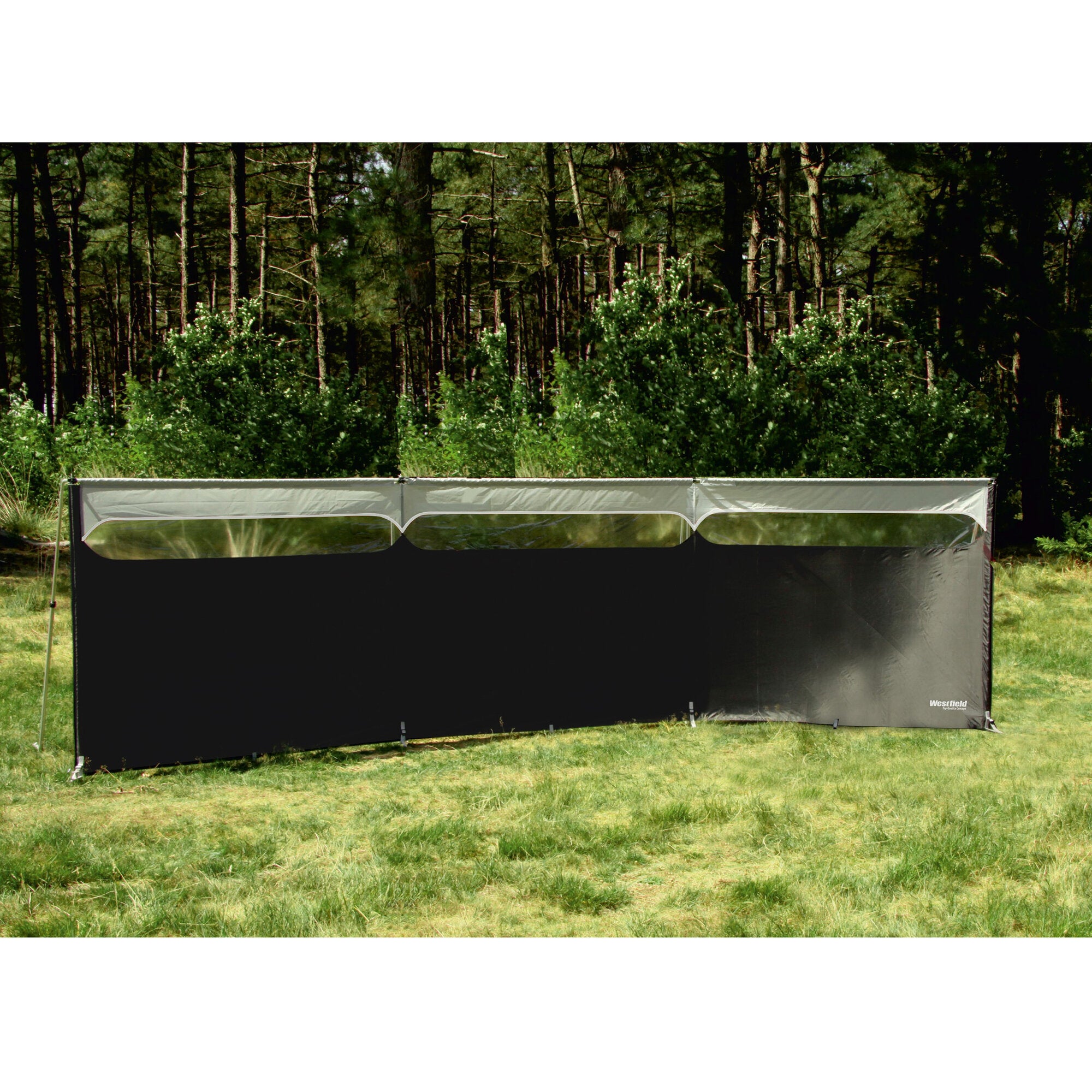 Windschutz Windshield Pro, breiter schwarzer Sichtschutz mit drei transparenten Fenstern, steht auf Gras vor Wald, Westfield-Logo unten