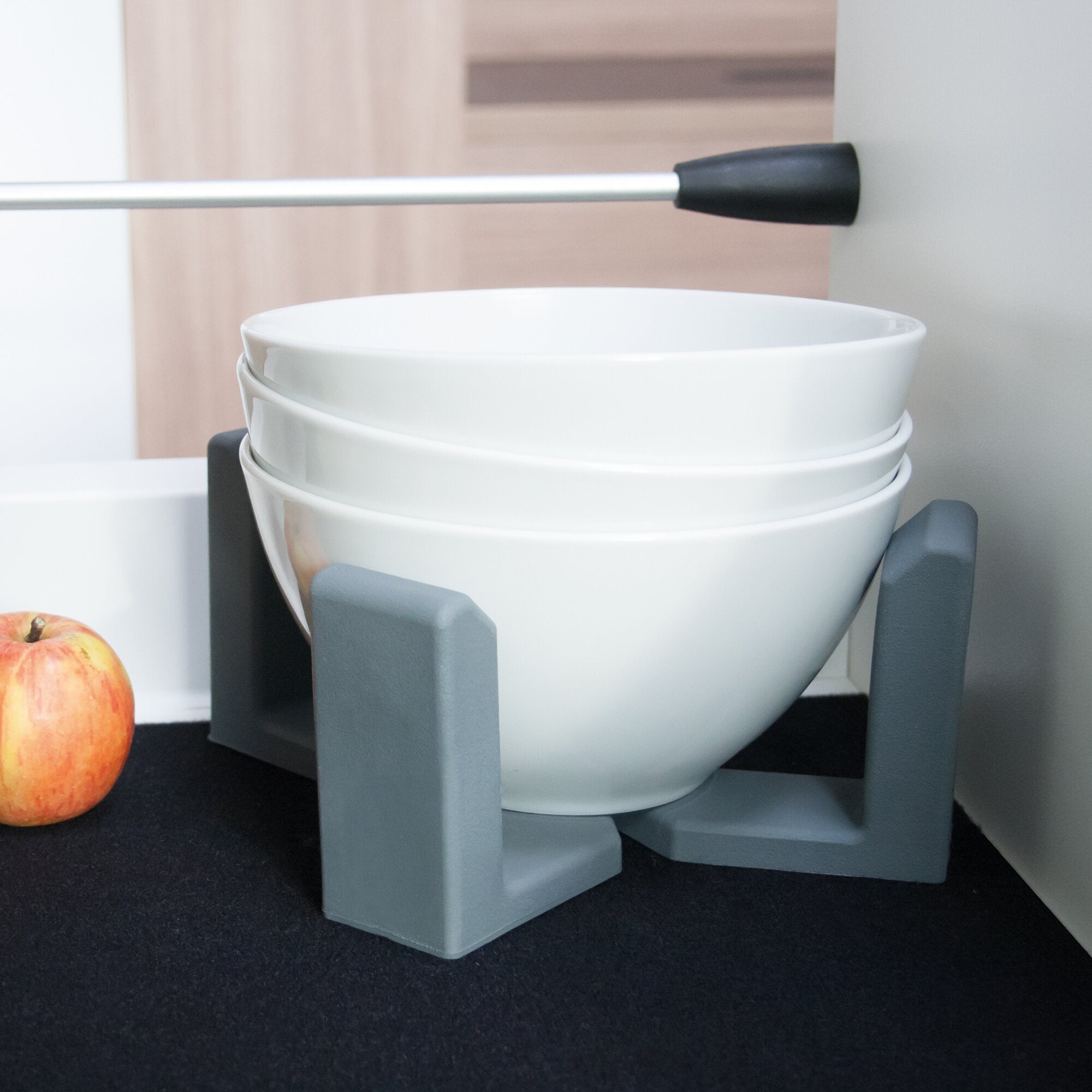 Vario System Modul III: Stapel weiße Keramikschalen in einem grauen Metallgestell, links unten roter Apfel, dunkler Untergrund