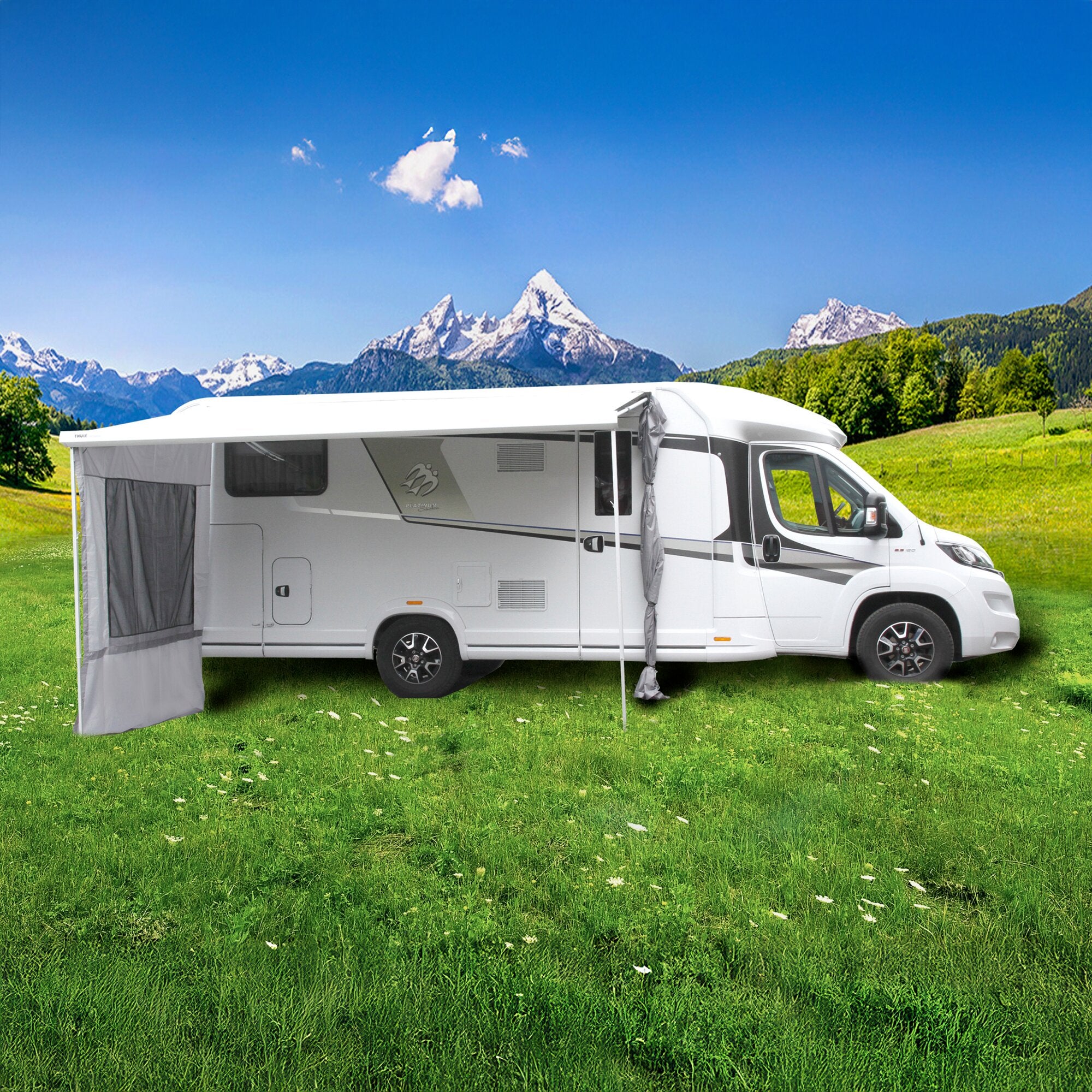 Weißes Wohnmobil mit ausgefahrenem Markisenzelt Camper Lounge, seitliche Vorbauwand, graue Tücher, grüne Wiese und Berglandschaft mit Schneebergen im Hintergrund