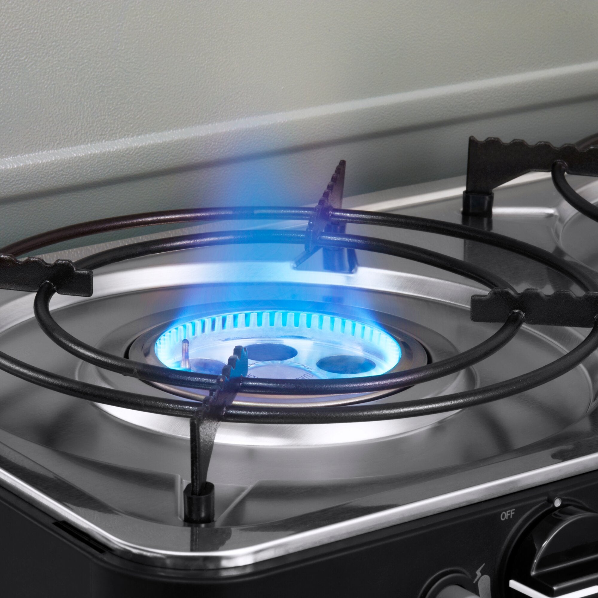 Gasbrenner eines Kochfelds mit blauer Flamme, runder Edelstahlkopf, schwarzem Brennergitter und Bedienknopf mit OFF an der Frontseite
