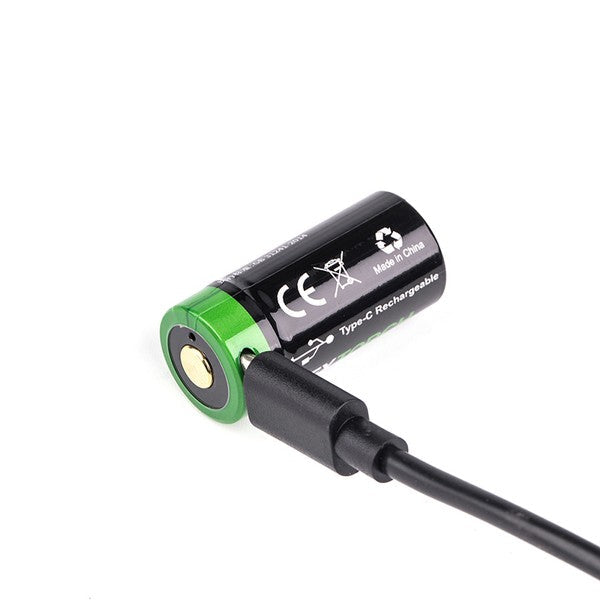 Schwarzer Li-Ion Akku NEXTORCH DC20061 16340 3,6 V 800 mAh mit grünem Pluspol, angeschlossener USB-C Ladekabel eingesteckt.