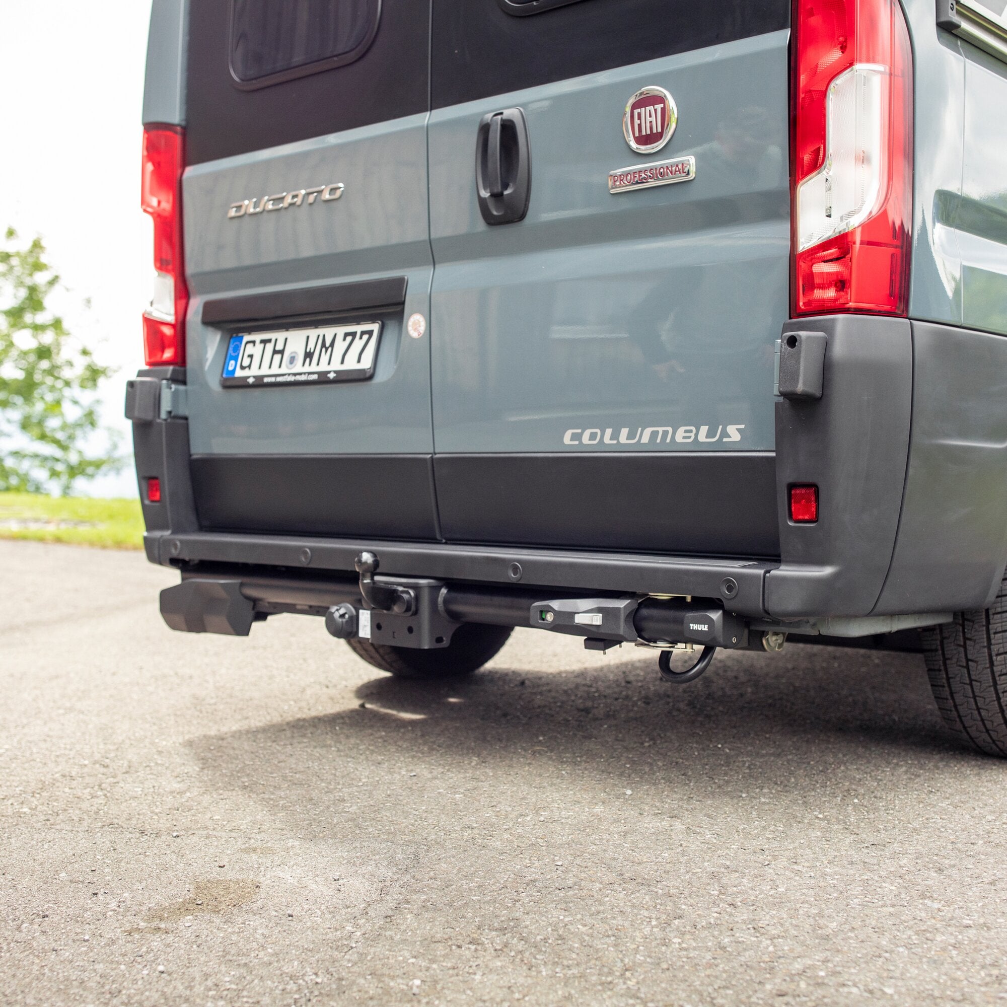 Rückseite eines grauen Fiat Ducato mit Thule VeloSwing-Halterung an der Heckstoßstange, Kennzeichen GTH WM77 sichtbar