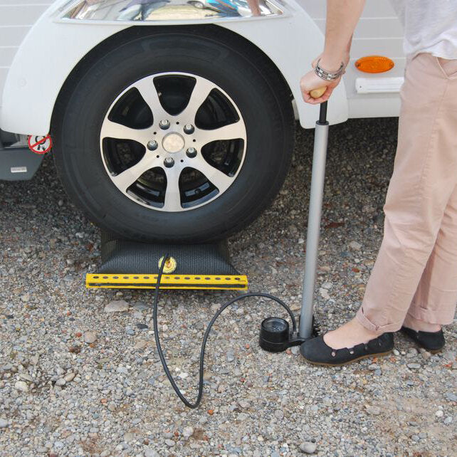 Autoreifen ruht auf gelbem Ausgleichskissen EMUK Air-Lift 2; Schlauch führt zur Handpumpe, daneben bedient eine Person das System