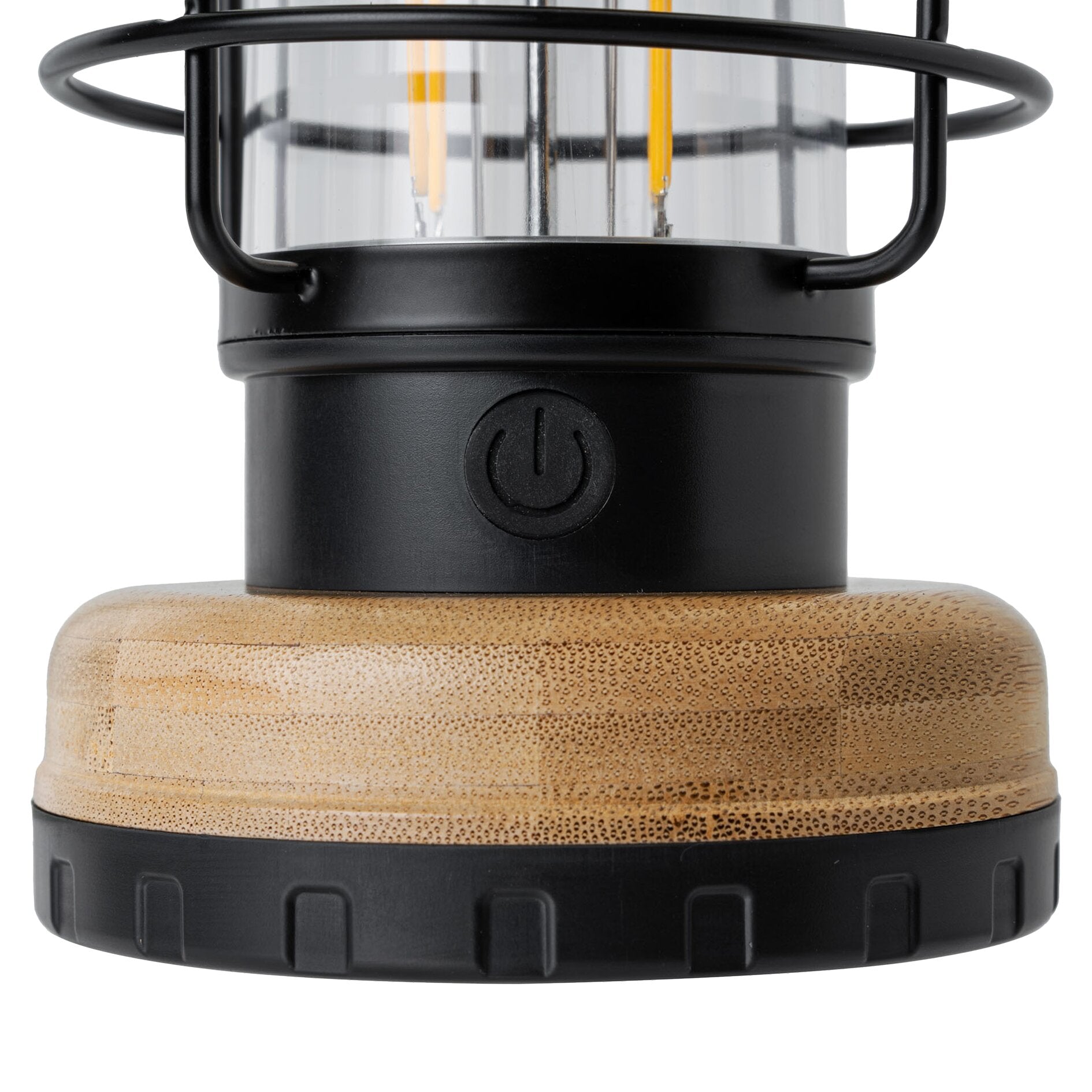 Nahaufnahme einer schwarzen Campinglampe mit Glasbehälter, Metallrahmen und LED‑Filamenten; runder Ein/Aus‑Schalter am Gehäuse, Holzsockel