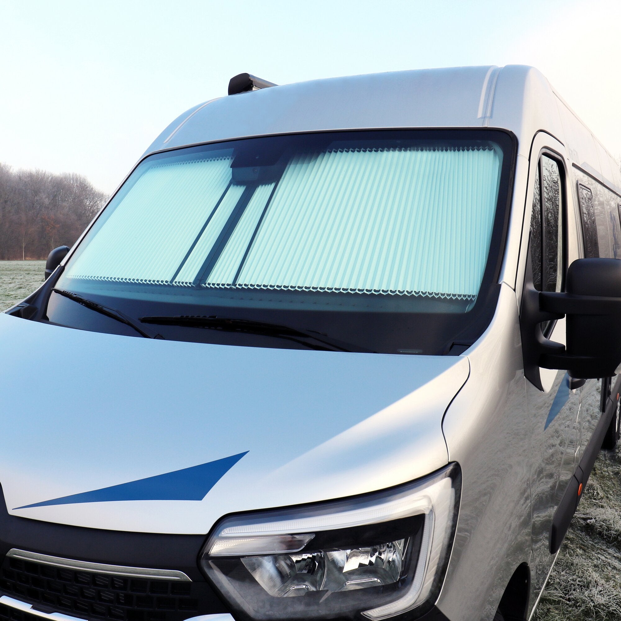 Weißer Transporter frontal, kleiner schwarzer Regensensor auf dem Dach, große Windschutzscheibe mit Wischern, Frontgrill und Scheinwerfer sichtbar
