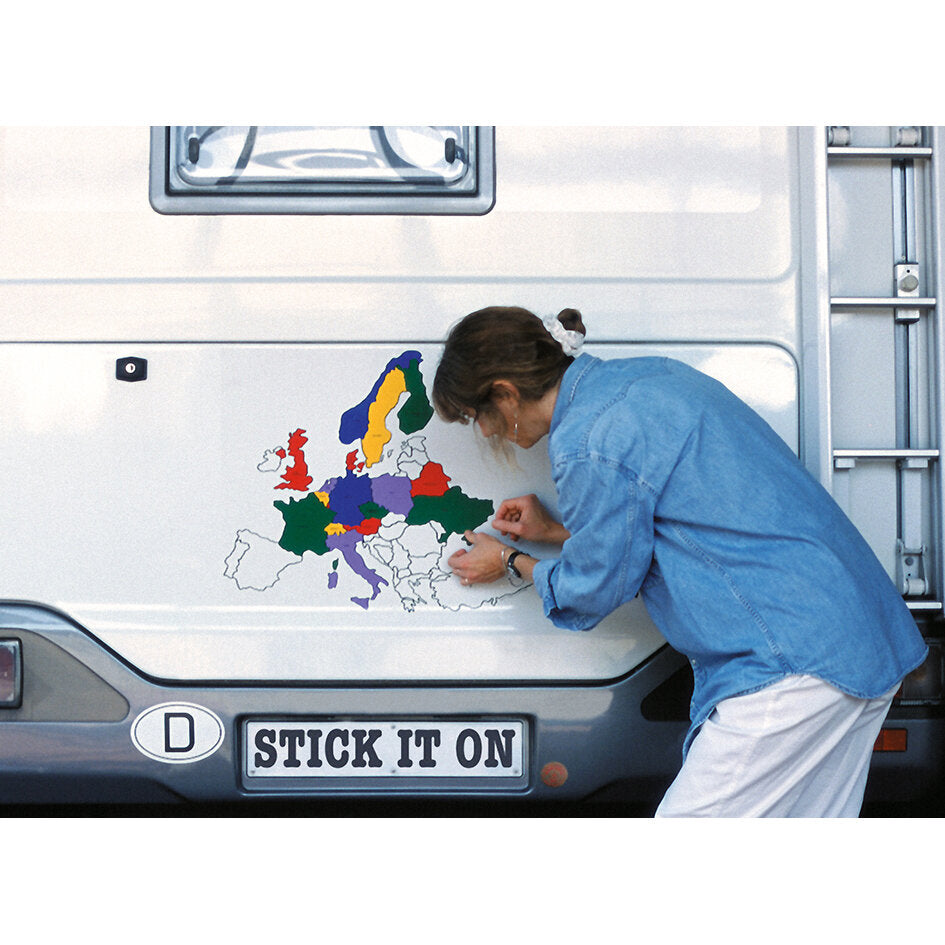 Eine Person klebt das Europa-Aufkleber-Set als bunte Länderkarte auf die Seitenwand eines Transporters; farbige Länderformen sind sichtbar