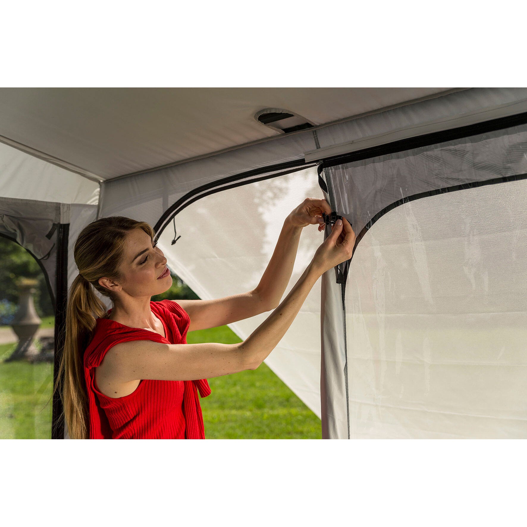Frau in roter Bluse im Innenraum eines Markisenzelts Privacy Ultra Light, 450 cm, befestigt einen Verschluss am Netzfenster