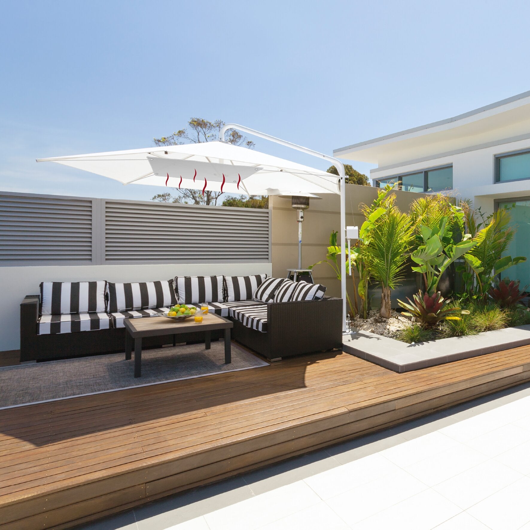 Terrasse mit weißem Sonnenschirm und Infrarotheizpanel darunter, rote Heizlinien sichtbar, davor eine schwarze Rattan-Couch mit Kissen