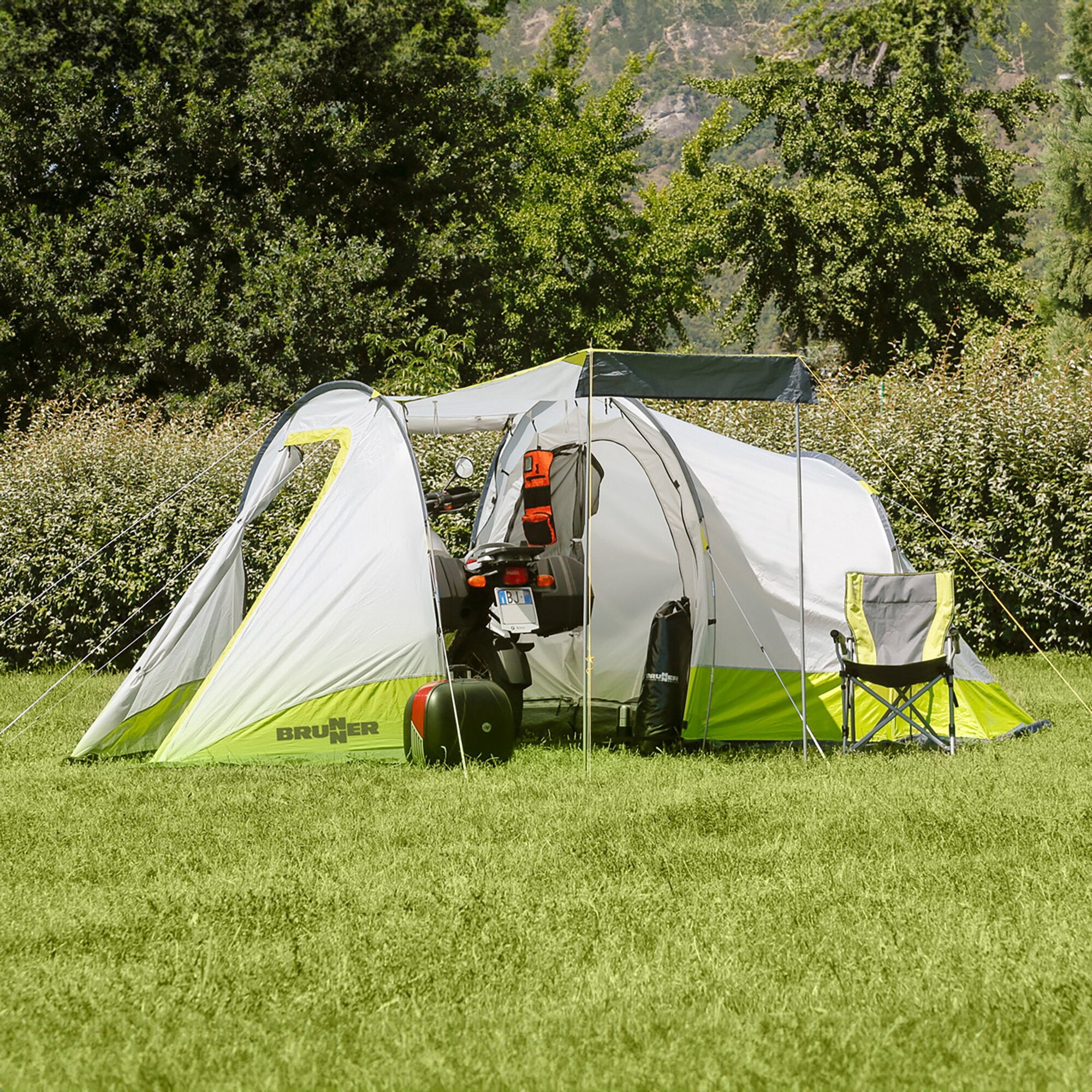 Brunner Zelt Atomic 3 in Grau mit neongrünen Boden, offene Front, Auto im Eingangsbereich, Gras und Bäume dahinter