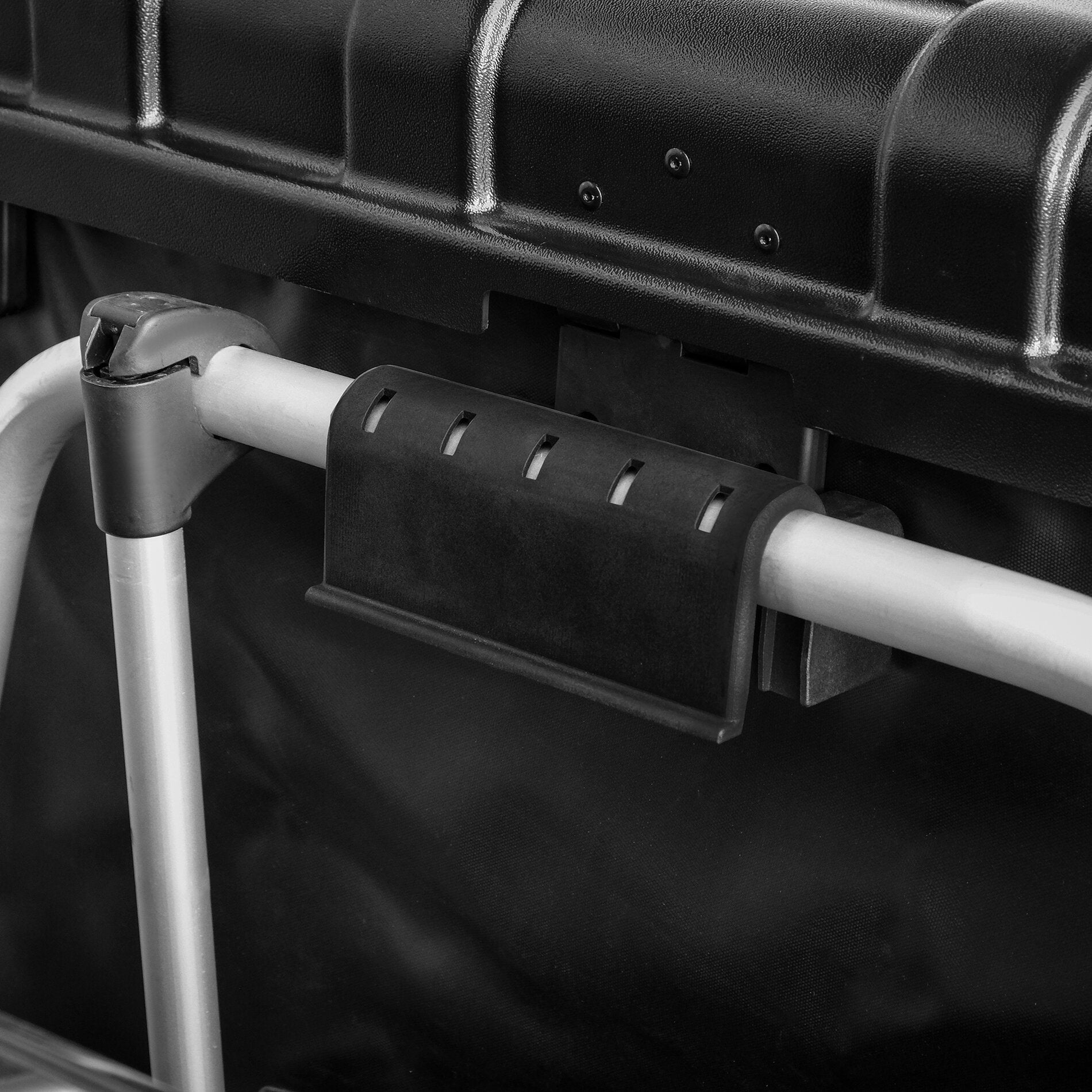 Detailaufnahme einer Transportbox aus schwarzem Kunststoff mit sichtbaren Schrauben, grauer Metallstange und Halterungsstück im Vordergrund