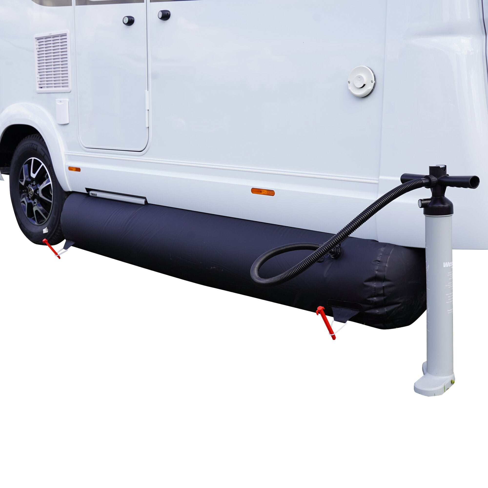 Seitenansicht eines weißen Vans mit einer aufgeblasenen schwarzen Bodenschürze am Unterboden, daneben eine Pumpe mit flexiblem Schlauch und rote Befestigungsteile