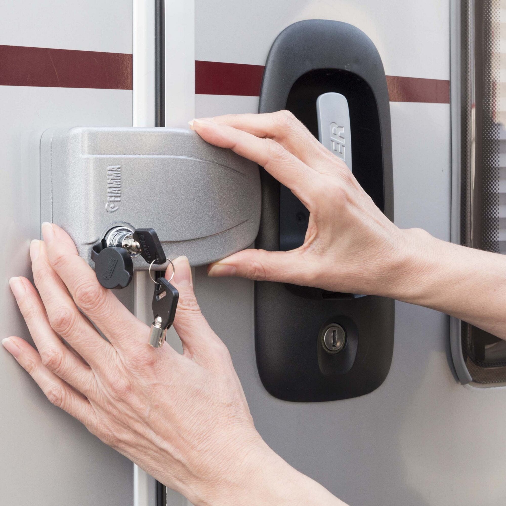 Detailaufnahme einer Hand, die eine graue Safe Door Türsicherung an einer Fahrzeugtür bedient, mit Schlüssel am Mechanismus