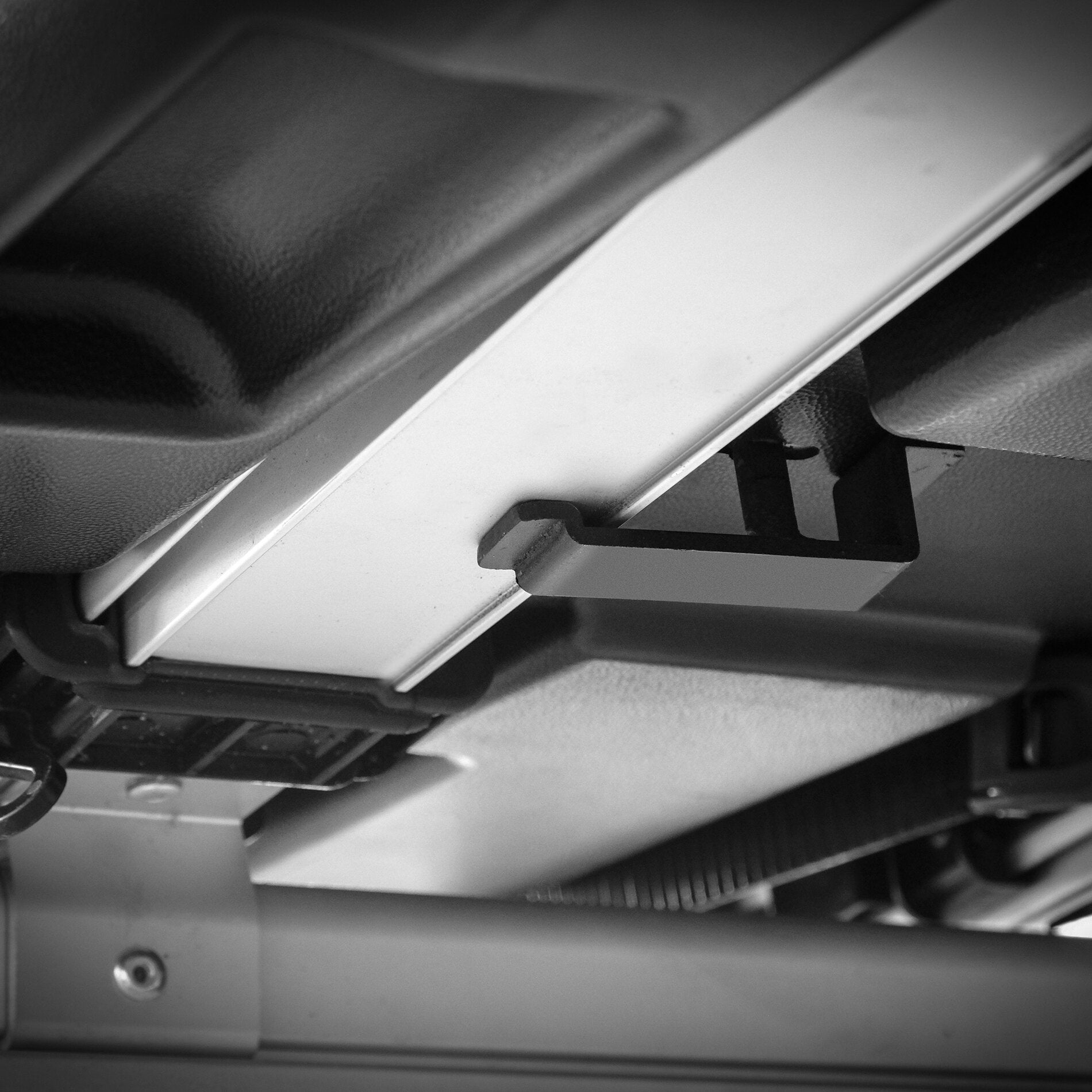 Detail eines Transportbox-Systems mit heller Führungsschiene aus Metall, dunklen Kunststoffteilen und montierten Halteklammern