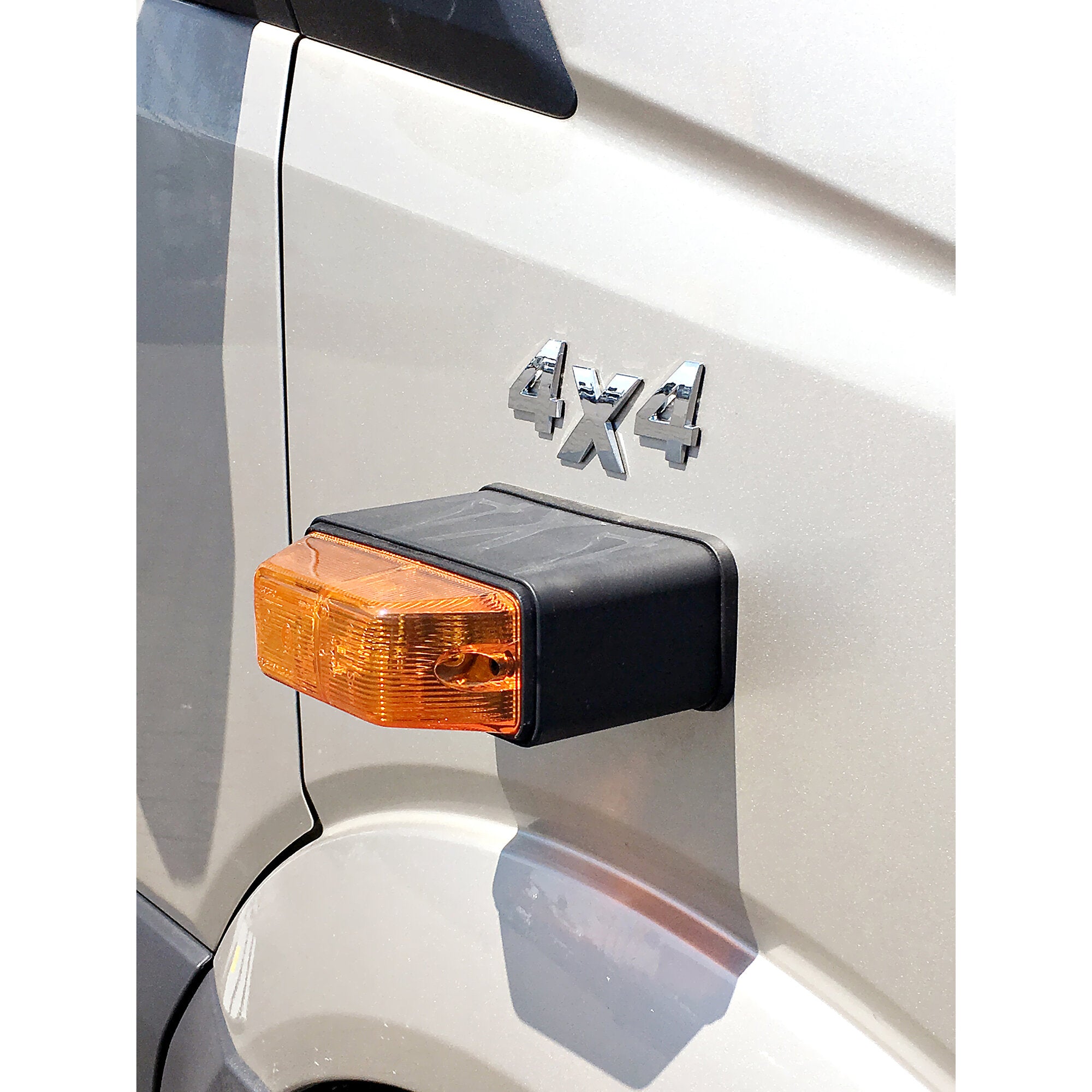 Nahaufnahme der Heckseite eines silbernen Vans mit orangefarbiger Blinkleuchte und dem chromenen 4x4-Emblem neben der Türnaht
