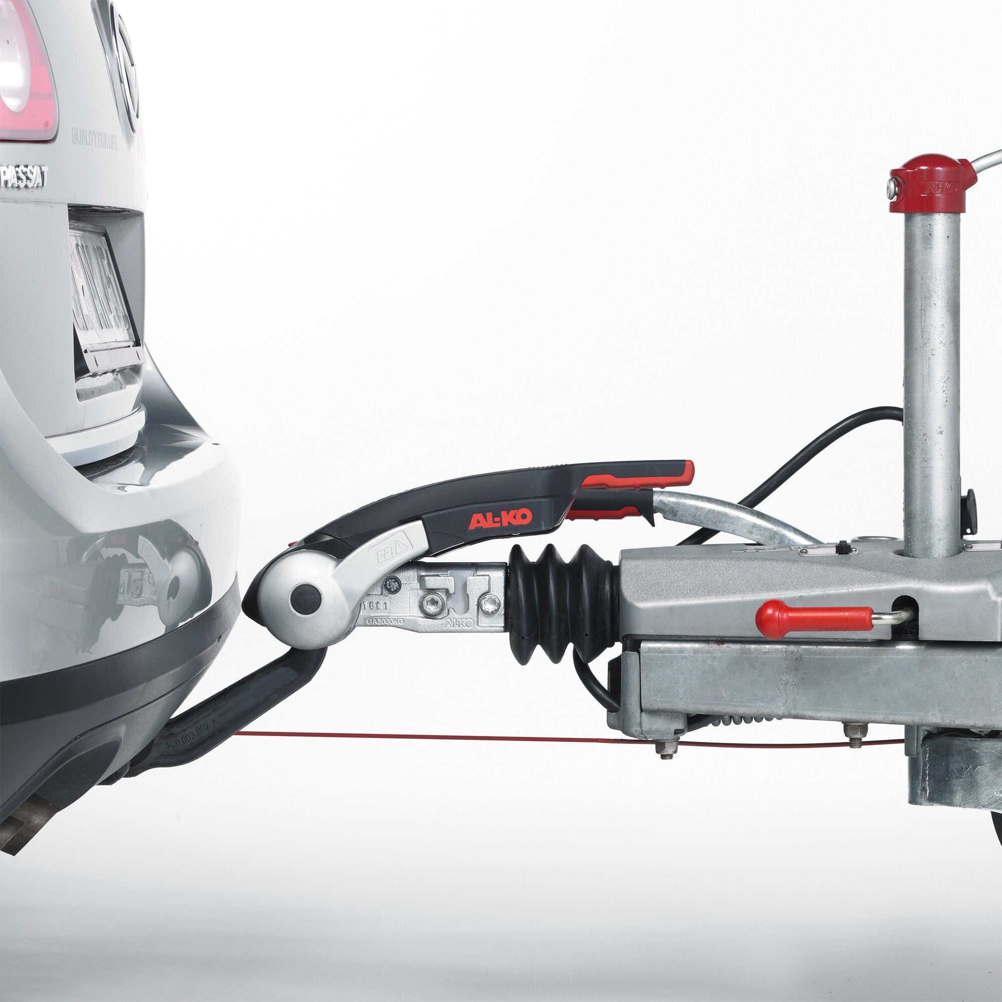 Detailansicht der AKS 3004 Sicherheitskupplung von AL-KO an der Anhängerkupplung, links das Heck eines silbernen VW Passat, rechts rote Abdeckung auf einer Metallstange