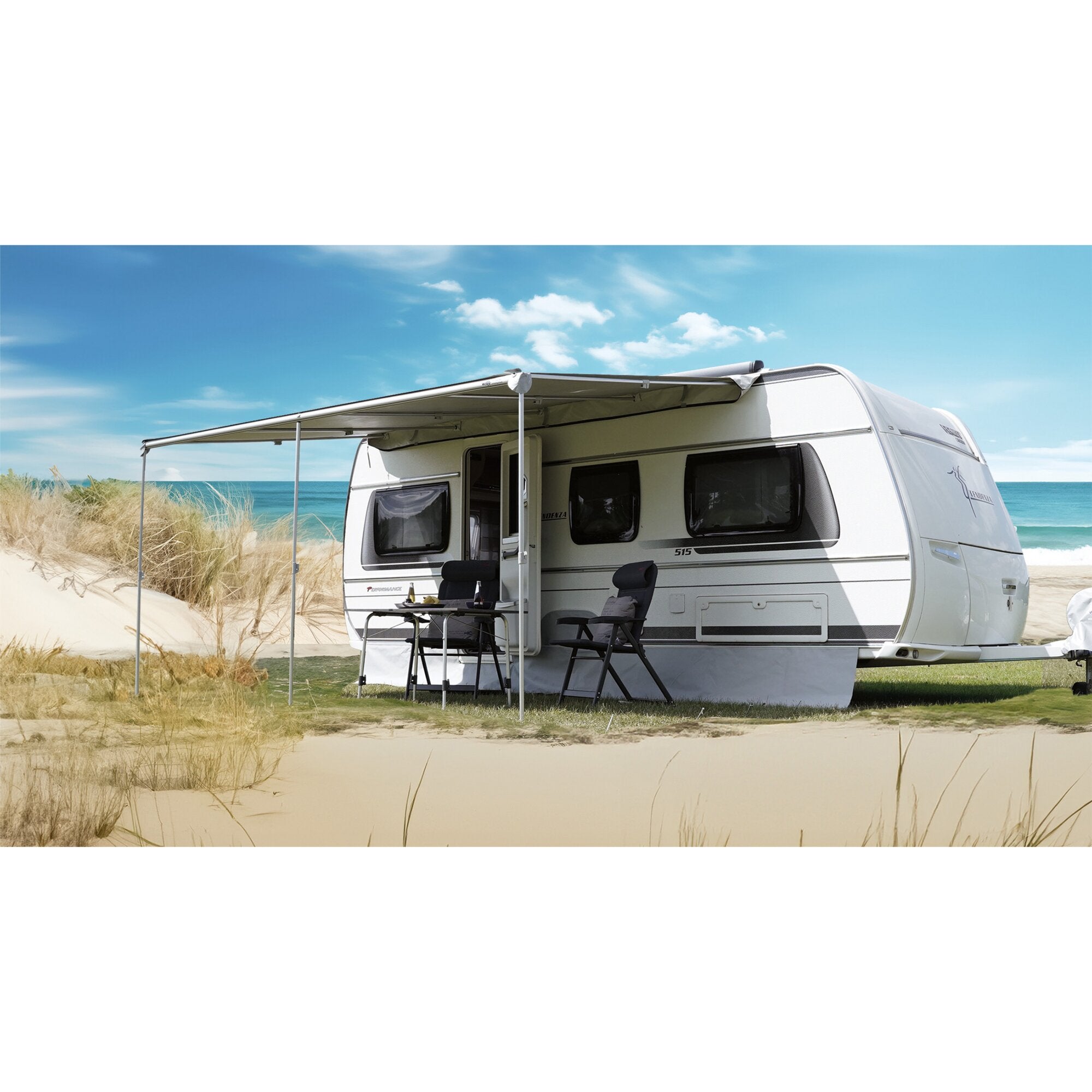 Sonnendach Breeze 450 x 235 cm über einem Caravan, mit Tisch und Stühlen davor, am Strand bei blauem Himmel