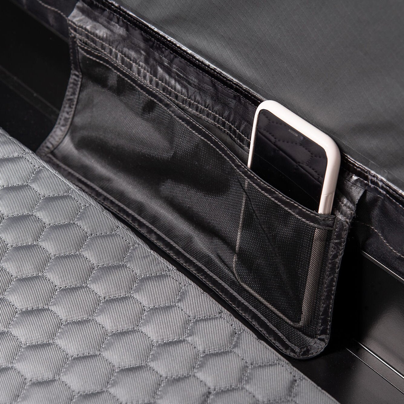 Detailaufnahme eines Smartphones in einem schwarzen Innenfach des Dachzelts Roof Space 2, umgeben von grauem Hexagon-Quiltstoff
