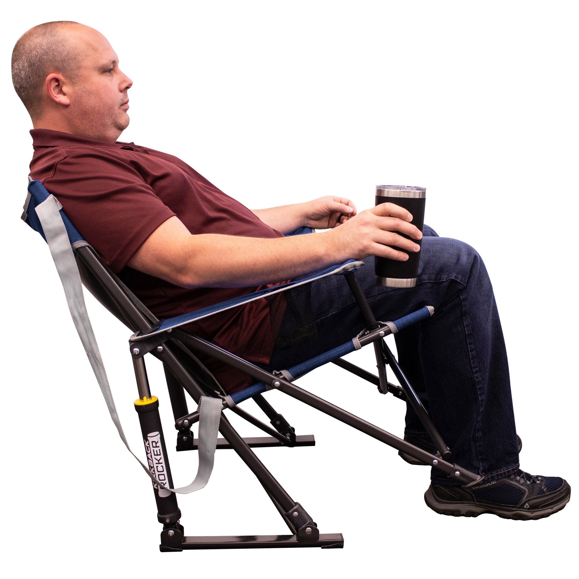Mann sitzt in einem indigo Camping-Schaukelstuhl Kickback Rocker mit blauem Sitz und schwarzem Metallrahmen, er hält einen schwarzen Edelstahl-Trinkbecher